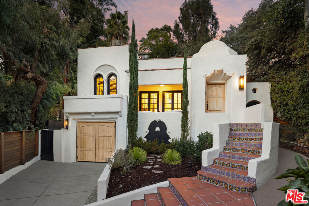 Tucked away on a quiet cul-de-sac, this 1923 Spanish Colonial with a Tuscany Flair blends timeless character with modern comforts, offering the perfect balance of privacy and convenience just moments from the Sunset Strip and iconic Chateau Marmont. Elevated above the street and framed by majestic trees, the home feels like a true retreat while staying connected to the vibrant heart of Los Angeles. Each of the three bedrooms opens directly to its own outdoor space, creating seamless indoor-outdoor living ideal for both quiet relaxation and inspired entertaining. Sunlight fills the interiors, highlighting original architectural details that harmonize beautifully with recent upgrades. Freshly painted inside and out, the home features restored wood floors, tile-accented foyers and terraces, and newly installed mahogany entry and garage doors that add warmth and craftsmanship. The updated kitchen is a chef's delight with marble countertops, a Wolf range, and a Sub-Zero refrigerator. The garage has been thoughtfully converted into a luxury gym, also perfect for a private office or studio. Modern upgrades, enhanced wiring, and a built-in gas grill make everyday living effortless. A terrace and private deck offer serene outdoor escapes with stunning sunset views, surrounded by trees that create a tranquil, retreat-like environment. Just minutes from world-class dining, entertainment, and culture, walking distance to the Sunset Strip. This rare offering captures the essence of Laurel Canyon living, a sanctuary of history, beauty, and comfort in one of Los Angeles's most iconic neighborhoods.