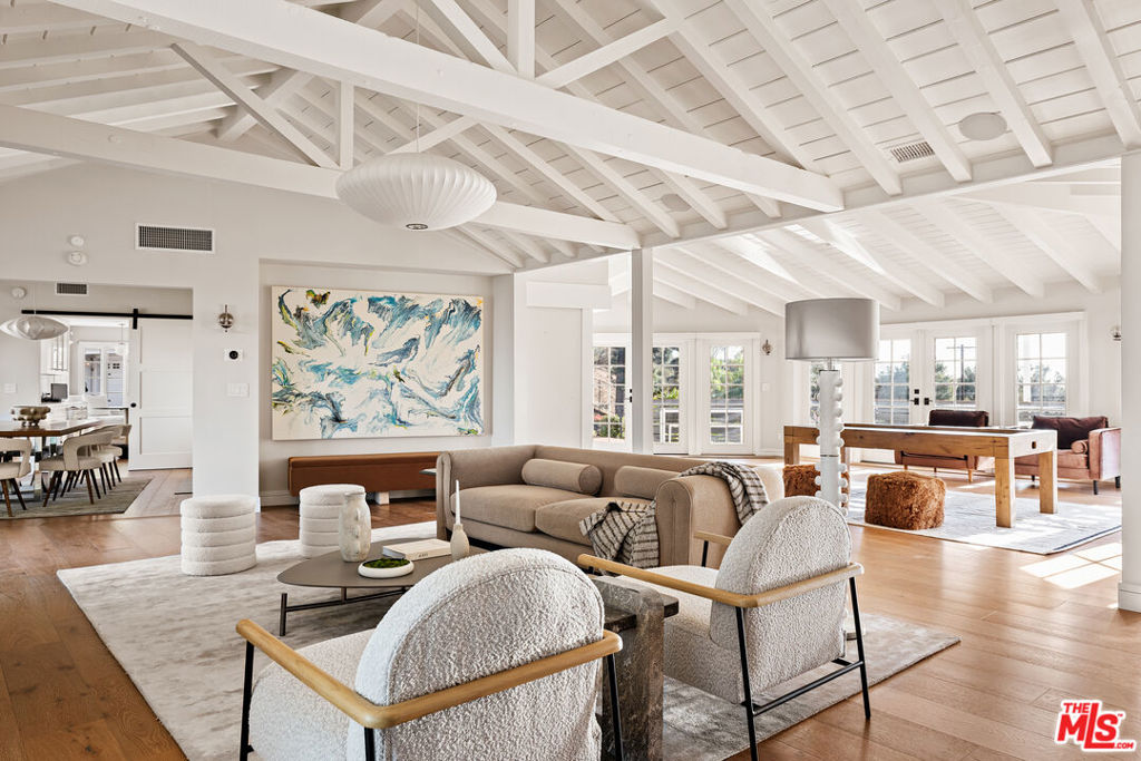 This beautifully renovated Robert Byrd original is perched on a private, tree-lined street just off iconic Mulholland Drive, offering tranquility and exclusivity while still boasting awe-inspiring 180-degree city and canyon views from both sides of the home. Set on a private road shared with only three homes, this single-story East Hampton Traditional seamlessly combines timeless design with modern living. The expansive living room, featuring cathedral-beamed ceilings and a stacked stone fireplace, flows effortlessly into a light-filled family room with walls of glass that open to an inviting entertaining deck. The stunning contemporary chef's kitchen, complete with state-of-the-art appliances, custom cabinetry, and Caesarstone countertops, opens to the formal dining room, creating the perfect layout for gatherings. The spacious primary suite offers a cozy stone fireplace, a luxurious en-suite bathroom with an oversized glass-enclosed shower, and tranquil views. Additional accommodations include a generous en-suite guest room and a private en-suite maid's room or office. Renovated in 2018, the home features exposed vaulted wood-beam ceilings, hardwood floors throughout, three fireplaces, and updated major systems. Outdoor living is reimagined with a brand-new sparkling pool, multiple dining patios with a gas fire feature, a custom BBQ area, a grassy side yard, terraced hillside gardens with fruit trees, and lushly landscaped private spaces. The property also includes a detached three-car garage and a motor court with space for 6-8 vehicles. With unparalleled privacy, breathtaking views, and access to nearby hiking trails, this home is a serene oasis that truly embodies the best of California living.