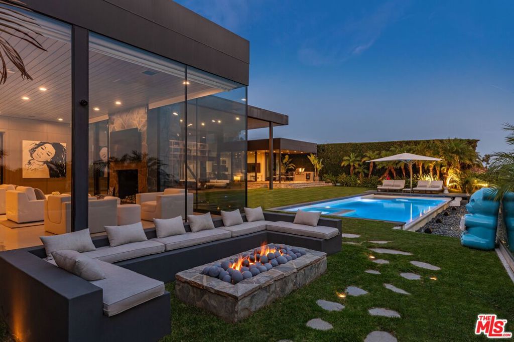 Elvis, Sinatra, Dean Martin: there's good reason that the world's style masters chose to call Trousdale home. Architectural tour de force in the most coveted location of Beverly Hills, Trousdale Estates. Originally designed in 1973 by renowned architect Amir Farr and reimagined by Belgian-born designer Maxime Jacquet, this Lautner-esque modern estate captures the essence of California living. Constructed from glass, steel, stone, and redwood, the residence spans over 8,000 SF and sits at the end of a quiet cul-de-sac. A soaring two-story living room with retractable glass walls frames sweeping city-to-ocean views and opens seamlessly to the expansive lawn, outdoor lounge, and infinity pool and spa. Inside, a sleek kitchen flows into the family room, while the interiors pay homage to the 1970s' open-space aesthetic with a sophisticated, earth-toned palette. The lavish primary suite offers its own lounge, stone fireplace, walk-in closet, and panoramic vistas. Designed for entertainment and relaxation, the estate includes a tiered screening room with state-of-the-art sound, fully integrated Crestron automation, and interiors that balance architectural drama with livable luxury in one of Beverly Hills' most exclusive enclaves.