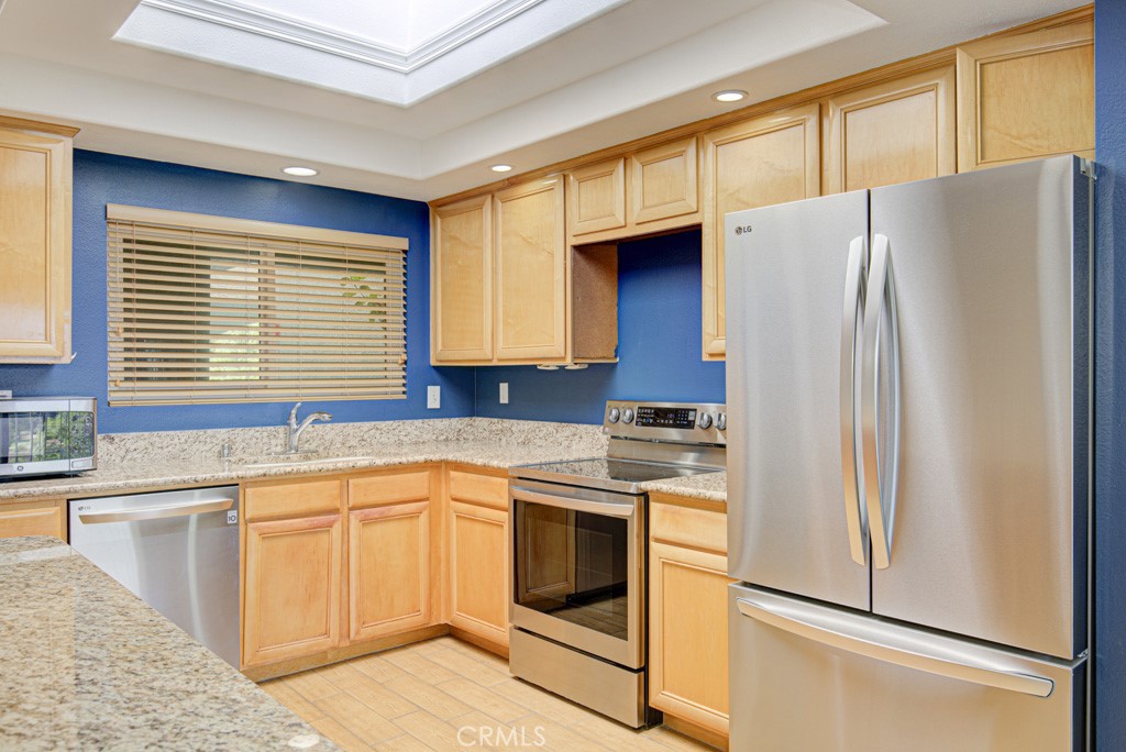 This Extraordinary Kitchen Has Been Transformed! Step inside this beautifully upgraded VILLA NUEVA model, where thoughtful design meets comfortable living. The heart of the home — an extraordinary, transformed kitchen — features custom cabinetry topped with luxurious slab granite and high-quality LG appliances. A rare skylight fills the space with natural light. Elegant ceramic tile floors mimic wood while offering water resistance. An ingenious bar under the arched opening connects the kitchen to the living room — perfect for a casual bite or storing large serving pieces. The kitchen opens to the dining area and living room, making entertaining easy. The dining room’s mirrored wall reflects the sweeping view through large glass doors, drawing your eye outdoors to the serene neighborhood and trees below. The generous living room features lush slate-gray carpet with extra-thick padding and a large dual-paned window that frames the view and welcomes coastal breezes. A central hallway leads from the front door through the main living areas, and in the opposite direction to bedrooms and bathrooms. The guest bedroom offers a peaceful view of the trees through dual-pane windows with plantation shutters, plush carpet, a large closet, and space for a queen-sized bed. The adjacent guest bathroom features a vanity, tub with newer shower door and fixtures. Welcome to the Primary Suite — your retreat. Large windows showcase serene views and plantation shutters allow you to control the light. The spacious bedroom easily fits a king-sized bed and large furniture. The Primary Bathroom features a double-sink vanity and step-in shower with updated glass doors. Oh, what a view! This home is perched atop a hill, surrounded by trees and greenery. Enjoy vistas of the neighborhood, glimpses of the wildlife preserve, and nearby access to the 73 Toll Road. Behind the building, you’ll find lush, HOA-maintained park-like landscaping. Ownership includes access to Laguna Woods Village’s resort-style amenities:100+ basic cable channels, water, sewer, trash included, Two golf courses: 27-hole championship and 9-hole par-3, Seven clubhouses, five pools, three fitness centers, 250+ clubs and social groups, Fare-free bus to shopping, dining, medical. All of this — just 6 miles from world-renowned Laguna Beach with easy access to the 73 Toll Road, 5, and 405 freeways. Welcome home to comfort, style, and an exceptional lifestyle at Laguna Woods Village!