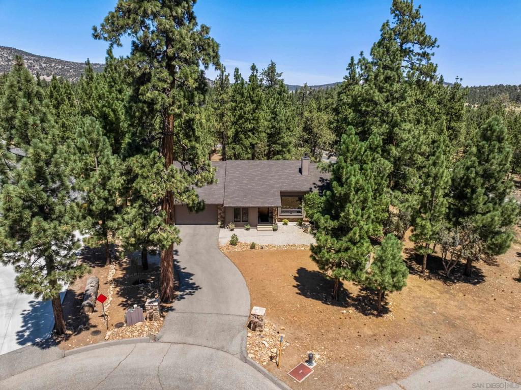 Welcome to Creekside Lane a true custom single-level home blending modern comforts with rustic charm on a generous 0.39-acre parcel fully fenced with rock columns and wrought iron fencing. From the hand-crafted wood ceilings and floors to the enchanting rock wall, every detail invites you to feel at home in this open-concept floor plan. The kitchen featuring richly hued slate counters, abundant storage, stainless steel appliances, and a spacious pantry opens to the living and dining areas. A window over the sink offers a perfect view of the custom wood deck, complete with built-in log seating and a serene backyard. Whether you’re enjoying a quiet morning coffee or hosting friends, your deck provides the perfect setting, surrounded by nature. The home offers three ensuite bedrooms, including a primary suite with a walk-in closet, double vanity with elegant finishes, and a roomy walk-in shower. The inviting family room boasts cathedral ceilings, a pool table, and a bar area ideal for gatherings. In the living room, a wood stove radiates warmth, while a large statement window frames stunning views of the trees and mountains. A separate workshop is ready for all your creative or handyman projects, and the laundry room includes ample storage. Parking is plentiful, with a two-car attached garage and an additional single-car custom container garage currently set up for a classic car. Sent from my iPhone LOCATED NEAR BIG BEARS TOP ATTRACTIONS SKI RESORTS- HIKING-BIKING-BOATING-FISHING- AND MORE