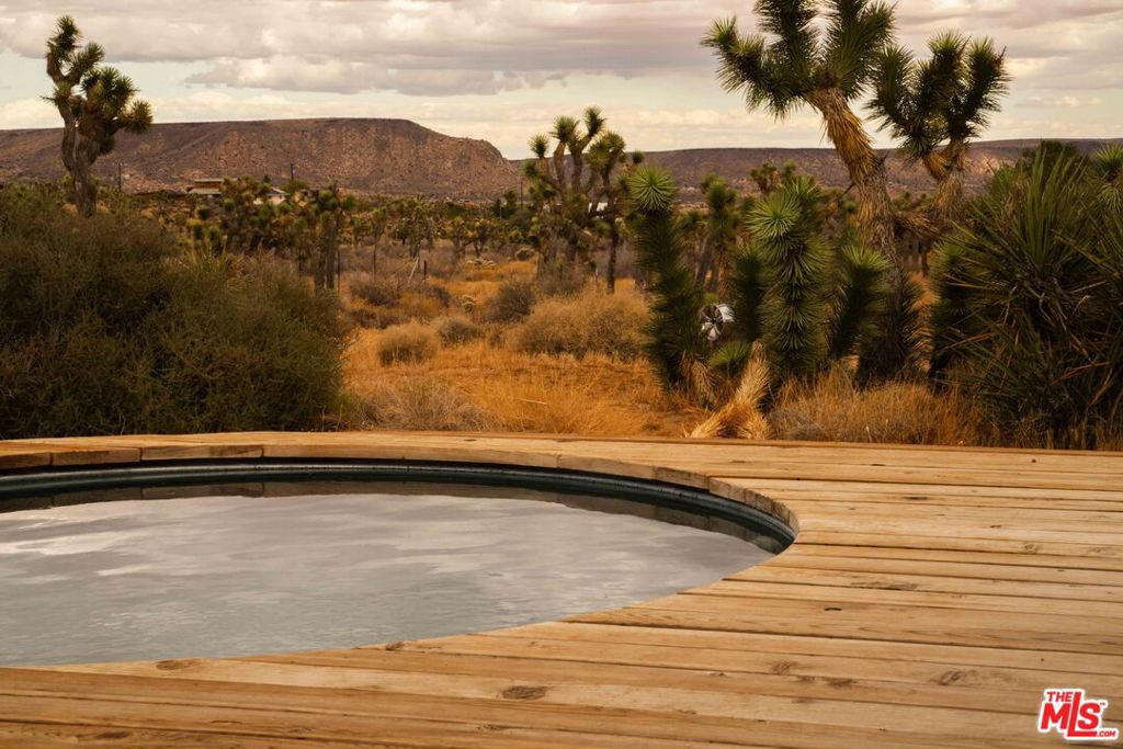 Welcome to your desert oasis. This tastefully remodeled home is the perfect retreat. Designed with an organic aesthetic -natural wood and warm tones that reflect the tranquility of the desert. You are absorbed with the beauty of the desert as you drive home, passing giant boulders and the vast desert landscape filled with Joshua Trees. You'll pass Pappy + Harriet's and The Red Dog Saloon and then just a few miles north of The Pioneertown Mountains Preserve to find Rimrock, a remote neighborhood in the coveted community of Pioneertown. Turn off the paved road and follow the loop to the driveway. From the front door, you'll appreciate the functional layout with your kitchen to the left, dedicated dining space, and living room complete with a charming wood-burning stove. Vaulted ceilings expand the space, drawing your attention to the kitchen and thoughtful design choices, including oak cabinets, butcher block countertop, a bay window nook, and new appliances. On the other side of the house is the guest bathroom, two bedrooms direct access to the garage. Both bedrooms have a dreamy bay window seat with extra storage, ceramic lighting fixtures, and concrete floors. The primary bedroom has an ensuite bathroom, walk-in closet, and a stunning view of the desert. An expansive deck stretches across the length of the home and features a built-in heated dipping pool and a private outdoor shower. The property sits on 2.49 acres with expansive views and epic sunrises and sunsets. The home neighbors Rimrock Ranch and is currently a Guest Favorite on Airbnb. Burns Canyon feels secluded, peaceful and a world away yet very accessible to amenities with The Pioneertown Mountains Preserve, The Red Dog Saloon, Pappy + Harriet's less than 5 miles away, Frontier Cafe, Mojave Flea Trading Post under 10 miles away, and many shops and restaurants along the 62. Seller is offering concessions. Inquire with your agent for more details.