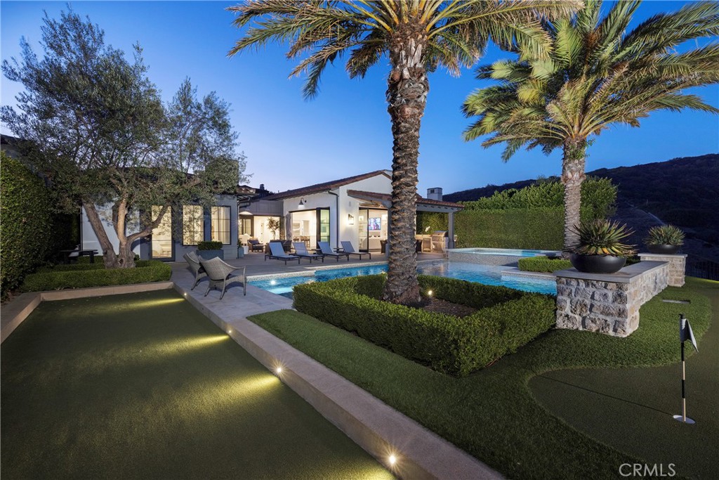Nestled within the prestigious 24/7 guard-gated and patrolled enclave of Crystal Cove, this beautifully upgraded and finely appointed residence offers the perfect balance of elegance, comfort, and resort-like amenities. With 4 bedroom suites and 4 ½ bathrooms, the home presents a light-filled, open floor plan designed to seamlessly connect indoor and outdoor living. The expansive flat main level features formal dining and living rooms, a gourmet kitchen, and a powder room, all flowing effortlessly to the rear courtyard anchored by an inviting outdoor fireplace. A private front courtyard leads to the detached guest casita above the two car garage with separate one car garage aside it, ideal for visitors or extended stays. The serene master suite enjoys sweeping views of the rolling California coastal canyons, complemented by a spa-like bathroom and finely appointed wardrobes. Expansive common areas and thoughtfully curated outdoor spaces invite year-round living and entertaining. The grounds are a true sanctuary, beginning with a turfed front lawn framed by mature, manicured landscaping and a tranquil water feature. In the rear, a resort-inspired pool with a baja shelf, spa, and cascading water features is surrounded by a bocce ball court, practice putting green, covered loggia dining area, BBQ pavilion, and multiple lounge spaces all hedged for maximum privacy and overlooking breathtaking canyon vistas. Crystal Cove residents enjoy access to the exclusive 2.5 acre Canyon Club, featuring swimming, tennis, basketball, meeting and entertaining spaces, along with four parks, lush green belts, and scenic hiking trails. Just outside the gates, the Crystal Cove Promenade offers premier dining and shopping within easy walking distance, while Crystal Cove State Beach lies just across Pacific Coast Highway.