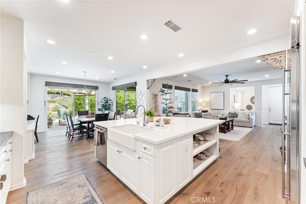 Beautifully upgraded and designed for effortless single-level living, this home is nestled within the exclusive 55+ Esencia community of Rancho Mission Viejo. Set on a large lot in a quiet location, this home offers outdoor spaces perfect for relaxing and entertaining. Inside, high-end builder finishes are elevated by professional interior design, creating a warm, sophisticated atmosphere. Premium wide-plank wood floors provide a seamless flow throughout. The open kitchen features an upgraded appliance package, quartz countertops, and a full-height designer backsplash. Just off the kitchen is a formal dining area for hosting dinner parties or enjoying quiet meals. The spacious primary suite is a retreat with a spa-inspired bathroom featuring dual shower heads, including a ceiling-mounted rain shower. The secondary bedroom also has an ensuite bathroom, ideal for guests. Additional upgrades include elegant built-ins, custom lighting, upgraded interior doors, designer window treatments, laundry cabinetry, and a finished garage with epoxy flooring and storage. The large office easily functions as a third bedroom. Step outside to your private backyard oasis with a California Room featuring a custom ceiling fan and fireplace, plus a pergola, stone pavers, and artificial turf. The immaculate backyard and side yards offer a perfect setting to enjoy Southern California’s year-round sunshine. As part of the 55+ community, residents enjoy resort-style amenities including pools, fitness centers, social events, clubs, and miles of walking trails. Style, functionality, and low-maintenance living in one of South Orange County’s most desirable communities.
