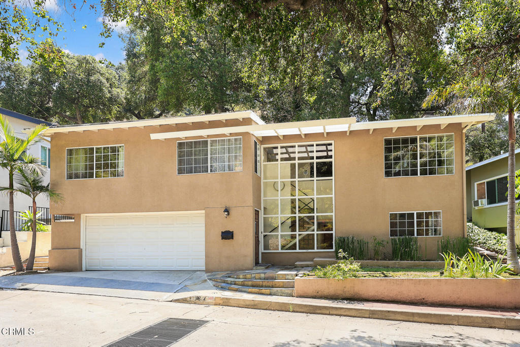 Tucked away on a private, tree-lined street in one of Glendale's most coveted neighborhoods, this luminous artist's retreat blends modern luxury with soulful character. Fully remodeled and infused with natural light from soaring two-story windows, this 3 bedroom, 3 bathroom home offers inspiration at every turn. The heart of the home is a warm and inviting living area with beamed timber ceilings, rich wood floors, and a dramatic granite-and-rock fireplace -- perfect for gathering, reading, or creating. The adjacent dining space opens to the kitchen with granite countertops, slate flooring, and stainless steel appliances -- a space that harmonizes function and beauty. A spacious entry-level bonus room complete with its own bathroom serves as a flexible studio, guest suite, or creative workspace -- ideal for a home office.Remodeled bathrooms feature elegant slate and granite finishes. Step outside to a backyard sanctuary full of wildlife with a grassy open area, brick accents, and lush landscaping -- the perfect setting for outdoor inspiration, morning yoga, or entertaining under the stars. With its slate-tiled entry and undeniable curb appeal, this home is a rare blend of privacy, artistry, and livable elegance -- a true haven for creatives and dreamers alike.Zoned for highly sought after Freemont, Rosemont and Crescenta Valley High schools.