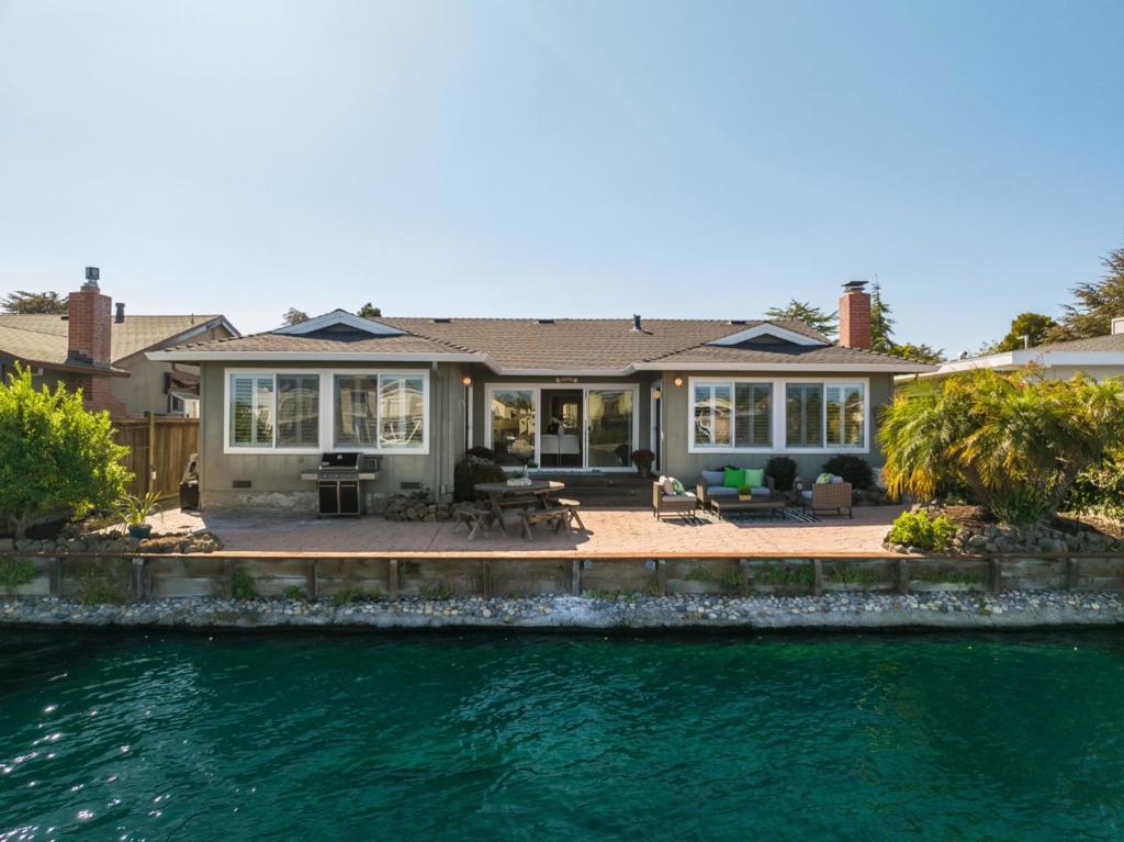 This exceptional single-level waterfront property offers breathtaking Wide Water Views & the added benefit of owned solar. This sun-filled home infuses the best of indoor/outdoor living with a wall of glass that opens to your gorgeous expansive view patio. With 3 bedrooms plus an office/flex room, there is plenty of space for family & guests. The heart of the home is the inviting living area, perfect for entertaining and everyday living. The well-equipped kitchen has seating for everyone with stone counters, a breakfast peninsula, & a functional layout that allows you to easily whip up culinary creations. The primary suite is a true retreat, complete with an en-suite & large windows that frame the picturesque views of the water, creating a tranquil atmosphere & separate access to the rear deck. The equally impressive outdoor space that leads directly to the water's edge is prime for al fresco dining and cozy evenings under the stars. Easy access to parks, shopping & top-rated schools.