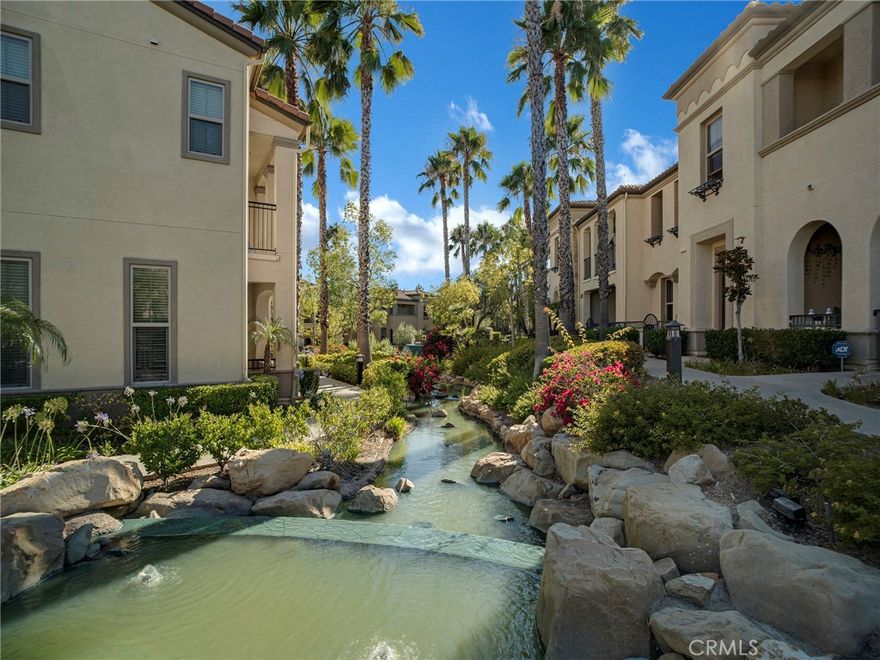 PORTER RANCH | Rare, updated waterfront unit in the coveted guard-gated Aldea community. This home is one of only a handful positioned in a serene setting, next to lush landscaping and soothing sounds of a cascading waterfall. From the moment you enter, the checkered tile flooring in the foyer sets a sophisticated tone. The first level features direct access to a 2-car garage, a dedicated laundry room with built-in storage, and a welcoming entryway. Upstairs, the layout unfolds beautifully, showcasing crown molding, hand-scraped hardwood flooring, plantation shutters and high-end light fixtures. To the right, a generously sized secondary bedroom and full bath provide comfort, privacy and flexibility. Straight ahead, the open-concept living space is drenched in soft, natural light and is a seamless blend of kitchen, dining, and family room that opens to a private patio. The kitchen is thoughtfully upgraded with granite countertops, stainless steel appliances, and abundant cabinetry. Privately tucked away at the far end of the home, the corner primary suite offers a peaceful retreat with mountain views. The fully remodeled en-suite bathroom features a spa-inspired shower, creating a luxurious escape, with endless hot water from the newer tankless unit. Living in Aldea means enjoying resort-style amenities: a sparkling pool, relaxing spa, BBQ area, and beautifully landscaped grounds. All this and just minutes from The Vineyards at Porter Ranch, top-rated schools, scenic hiking trails, and convenient freeway access. Don’t miss your chance to own one of Aldea’s rare waterfront gems — a true blend of luxury, location, and lifestyle.