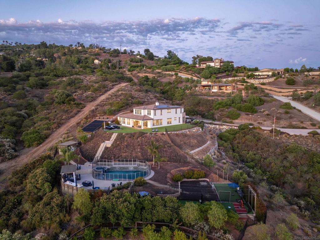 Poised on a premier view lot high above the valley, this one-of-a-kind residence in Highcrest Court Estates offers an extraordinary lifestyle experience. This design-forward and stunningly appointed executive estate is the epitome of refined luxury. Situated on an expansive 2.01 acre lot, with editorial-worthy finishes, no detail has been overlooked. Built by Vesta Pacific in 2018, with Mediterranean-inspired architecture, the home is masterfully positioned to take full advantage of its unobstructed, panoramic views and natural surroundings. Step inside to discover an open-concept layout, an entry-level primary suite, a chef-caliber kitchen with top-tier appliances, and expansive living spaces ideal for both everyday comfort and elevated entertaining. A dedicated study area and oversized loft offer flexibility for work or play. Energy-efficient features include owned solar, a TESLA electric car charger, LED recessed lighting, dual tankless water heaters with on-demand pumps, radiant roof barriers, two-zone HVAC with programmable thermostats, and low-VOC paint. Newly painted inside and out in 2024.The exterior is nothing short of a private resort. Enhancements include a solar-heated, saltwater pool and spa, elevated view deck, putting green, fitness zone, two BBQ areas, artificial turf, batting cage, outdoor shower, and multiple lounging areas, all curated to create an entertainer’s dream or private retreat. This extraordinary property is also located within the boundaries of Poway’s award-winning schools. The long private driveway ensures plenty of parking and privacy, seamlessly blending sophistication, innovation, and lifestyle, this is Southern California living at its finest.