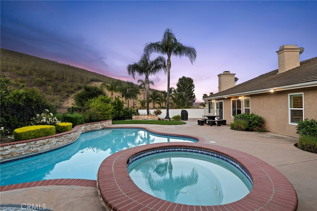 Kimberly Drive is a highly coveted street located in the Morrison Ranch Highlands where single story homes rarely hit the market. What makes this home highly desirable is its location at the top of a hill on a cul-de-sac. The approximately 13,000 sqft lot showcases a pool, spa, citrus fruit trees, mature landscaping and a captivating hillside view with tons of privacy. Your new single story home features four bedrooms, three and a half bathrooms, a three car garage with EV charging and approximately 3,039 sqft all on a lot that is both flat and impressive with its panoramic views. Beautiful hardwood floors and vaulted ceilings greet you as soon as you walk into the property. The chef's kitchen was remodeled with new cabinetry, quartz countertops with matching backsplash, stainless steel appliances and a walk-in pantry that also serves as the laundry room. The open concept kitchen boasts a dining area and flows into the family room that has been expanded and features both a gas fireplace and a wet bar area. The mountain views can be seen from the spacious family room which has a sliding glass door leading to your entertainer's backyard. There is also a formal dining room as well as an adjacent living room which has a gas fireplace and beautiful bay windows. Leading to the primary suite is a stunning atrium that can be used for multiple purposes. The spacious primary suite has views of the mountains and features vaulted ceilings, a large walk-in closet and an ensuite primary bathroom that has dual sinks, a walk-in shower, soaking tub and gorgeous stone floors. There are three additional bedrooms, one of which has an ensuite bathroom with a walk-in shower. In the hallway is a large guest bathroom with a walk-in shower plus there is an additional half bath for guests near the front foyer. Located in the prestigious Las Virgenes Unified School District, where all three assigned schools for this home have earned blue ribbon designations. Your new home is also a short drive to the popular Yarrow Family YMCA, the famous Promenade shopping center, the Lake Lindero Golf Course, multiple parks, Malibu beaches and more. Welcome home to one of the best neighborhoods in all of Agoura Hills.