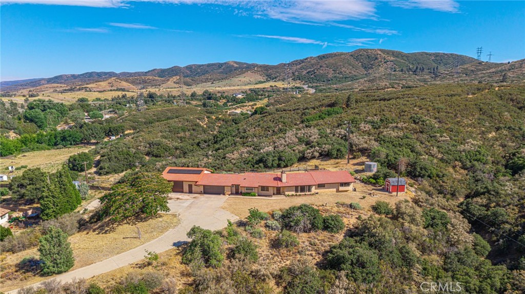 Perched above Elizabeth Lake in the tranquil hills of Lake Hughes, this private 5-acre ranch-style home offers breathtaking, unobstructed views and the ultimate blend of nature, functionality, and comfort. Set within a close-knit rural community, the property provides a rare opportunity to enjoy expansive open space while remaining connected to modern necessities — ideal for remote work, creative pursuits, or simply escaping the daily grind.
The 2,078 sq ft main residence features 3 bedrooms and 3 bathrooms, including a versatile third bedroom located off the kitchen, perfect for use as a home office, studio, or private guest suite with its own bath. The spacious living room invites relaxation with vaulted ceilings, windows framing mountain vistas, and a striking wood-burning fireplace that anchors the space. Glass sliding doors lead directly from the living room to the back patio, creating a seamless indoor/outdoor living experience.
The updated kitchen offers newer countertops, a picturesque garden window, and stainless steel appliances. It opens to a dining area framed by custom built-in cabinets and a buffet, adding warmth, storage, and charm to everyday meals or entertaining. Adjacent, the laundry room doubles as a functional dog-washing station and extra pantry space.
Outdoors, the home is thoughtfully designed for both practicality and enjoyment. A generous workshop with 220v power and insulation is ideal for car enthusiasts and hobbyists, while the attached 2-car garage features an insulated, automated door and direct access to the house. There’s ample space for RV and boat parking, as well as room to expand or build out your vision.
The backyard is fully fenced with snake-proof mesh and includes a peaceful patio area for evening unwinding, a Tuff Shed for additional storage, and a fully enclosed dog run with indoor access. The property is outfitted with leased solar panels (buyer to assume) and includes a non-working well with potential for restoration—offering energy efficiency and the foundation for future off-grid living.
Located within close proximity to both the Santa Clarita Valley and Palmdale, there's convenient access to the greater LA area, while still feeling worlds away from it all. Nearby hiking trails and community events add to the lifestyle appeal, making this an ideal setting for those seeking privacy and opportunity.