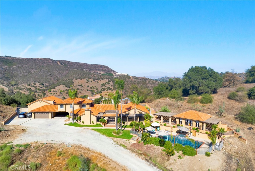 Welcome home to this stunning Mediterranean-inspired estate, set amidst the breathtaking views of Temecula Wine Country. Nestled on 8.63 peaceful acres of rolling land, this property offers the perfect balance of tranquility and luxury. The main home spans a generous 3,579 square feet and has recently undergone an extensive, high-end remodel. It features a beautifully appointed main-level primary suite, a junior suite, a guest bathroom, and a separate laundry room with ample storage. Upstairs, you’ll find an additional suite with two bedrooms, each with its own closet, and a shared full bathroom. The heart of the home is the chef’s kitchen, complete with top-of-the-line appliances, stunning "Knotty Alderwood" cabinetry, sleek granite countertops, and a cozy breakfast nook. The great room boasts a stately Venetian plaster-style fireplace, while the formal dining area offers the perfect setting for dinner parties. Step into the living room with a second fireplace, adding elegance to the living spaces. Throughout the home, you’ll enjoy beautiful engineered hardwood flooring, complemented by gorgeous tile and stone accents in the bathrooms. Multiple patios, including an expansive covered patio system, provide plenty of space for outdoor living. The outdoor cabana-style room with a mounted TV is perfect for entertaining, while the uncovered firepit patio overlooks your sparkling pool and spa—ideal for relaxing and unwinding. For extra versatility, an attached bonus room near the covered carport offers a great space for additional sleeping quarters, a gym, or a flexible room to suit your needs. The detached, two-story, 6-car garage is a true standout, featuring roll-up doors, a bonus/office space with a beautiful cabinet and sink, and an additional upstairs studio. The amazing backyard has panoramic views, multiple patios, planter boxes and pots around the backyard, along with a pickleball area and putting green. Additionally, there is a spacious chicken and small animal coop, plus 2 more small animal stalls on the lower level. With its stunning outdoor spaces, captivating views, and quality upgrades throughout, this property offers everything you could want in a home. There’s truly no place like it!