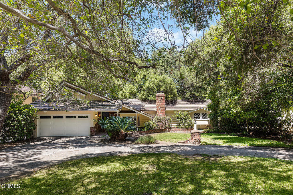 Tucked away on a quiet tree-lined drive in La Canada Flintridge, this 1961 character home rests on a rare, flat and lush 16,000 square foot lot embraced by majestic oak trees. This serene setting offers both privacy and possibility, from peaceful garden living to future expansion. With recent updates of new HVAC, new floors, remodeled bathrooms, recessed lighting, new copper plumbing, tankless water heater, interior and exterior painting, and more. Inside, architectural details unfold in the living room with high wood-beamed ceilings, a brick fireplace, built-in bookcases, and new wide-plank wood-like floors. A diamond-lattice window graces the adjacent dining area, adding vintage charm. The bright kitchen retains its freshly painted cabinetry, stainless steel appliances, new white countertops and a garden-view breakfast nook beneath wood beam accents. A Dutch door leads to the patio perfect for entertaining or quiet evening gatherings. The sunlit primary bedroom features a wall of closets, new floors, and sliding glass doors opening to the expansive patio and lush grounds beyond. A shared hallway full bath, remodeled with serene finishes, a double vanity, and large shower, connects to a generous front bedroom with a charming window seat. A third bedroom and 3/4 bath are situated conveniently near the laundry room with direct garage access. Up a short flight of stairs, a private office or den with vaulted wood ceilings and new floors offers treetop views--an ideal creative hideaway or work-from-home space. A circular driveway with an attached two car garage offers an abundance of parking. With its sprawling, usable backyard with room for expansion, this property invites outdoor living, landscape design, or even a pool addition. Whether you are moving right in or building your dream home amongst this storybook setting, This is a rare and beautiful opportunity in La Canada Flintridge!