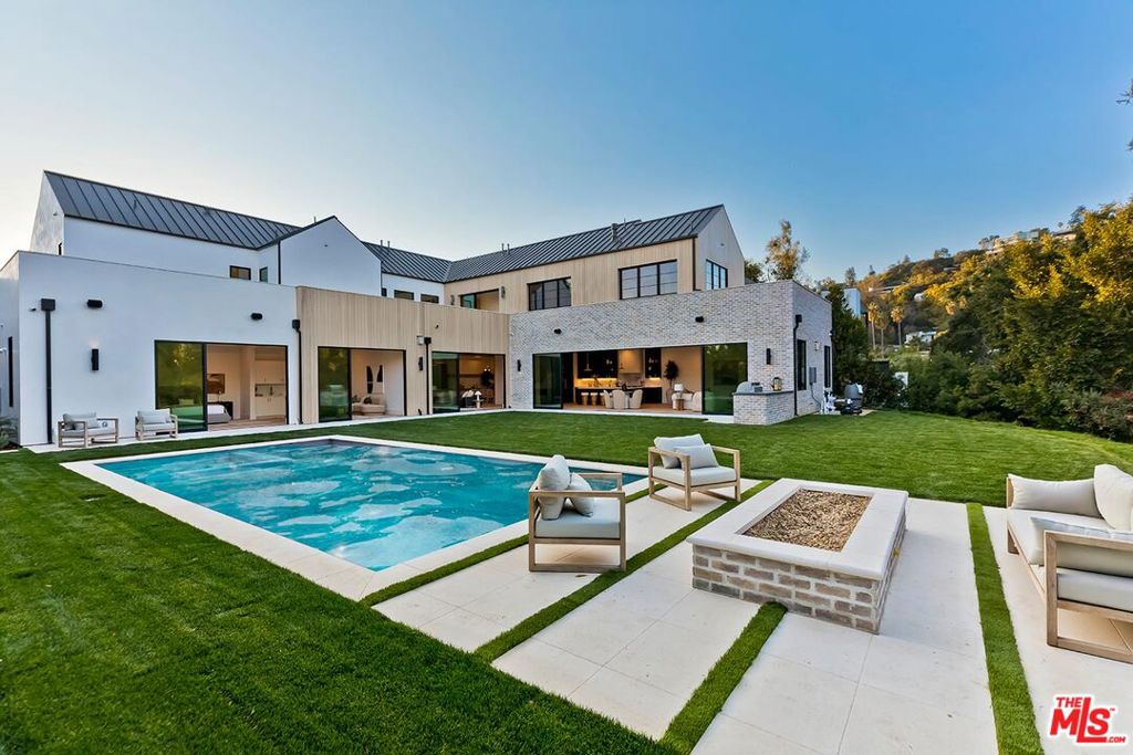 In the heart of the prestigious lower Beverly Hills Post Office area, this brand new construction Modern Farmhouse redefines luxury and sophistication. Set on an expansive flat lot of 14,000 square feet, the residence exudes timeless elegance with a warm contemporary design that invites natural light and nature into every corner. Boasting 5 bedrooms and 5.5 baths, this stunning home perfectly blends upscale amenities with serene, open interiors designed for both entertaining and everyday living. Step through the two-story entry into a light-filled oasis where organic materials like bleached wood siding, white oak floors, and vaulted ceilings create an atmosphere of tranquility. The thoughtfully designed floor plan seamlessly flows from living and dining rooms to an expansive great room with retractable walls of steel and glass opening to a resort-style backyard. Beautiful chef's kitchen with butler's pantry and extraordinary Argento Marble center island. Primary suite aerie with vaulted ceilings, spacious closets, and private terrace. Primary bath with handsome Grigio honed stone adorning shower, vanities, and fireplace. Three additional bedroom suites up and practical 2nd floor laundry. Main level stylish bedroom suite ADU opens to sparkling pool, BBQ for dining alfresco, and spacious, grass lawn. Captain of Industry office through architectural reeded steel doors. Dedicated first floor gym. Control 4 home automation. Located moments from the finest Beverly Hills, Westside, and Southern California amenities, this extraordinary estate offers a rare opportunity to experience unparalleled luxury and privacy in a warm, serene setting.