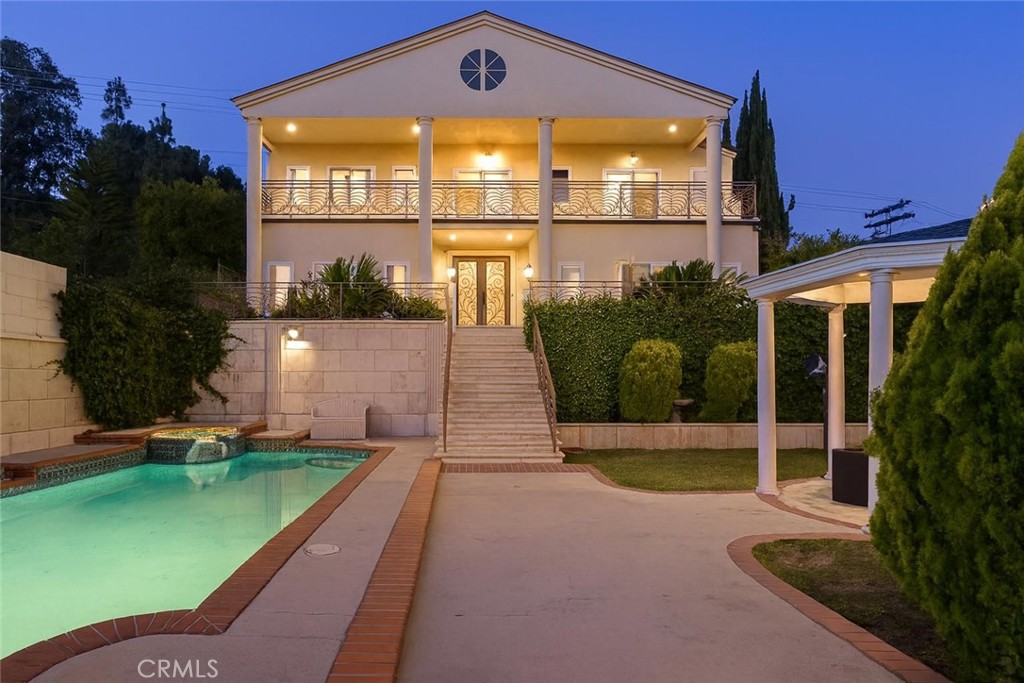 This custom-built home in one of Glendale’s best neighborhoods is a luxurious retreat. Enjoy a resort-style front yard with a sparkling pool and spa, brick-trimmed patio, and a white gazebo surrounded by palm trees and manicured landscaping. The two-story exterior stands out with tall columns, wrought-iron balconies, and warm stucco. Inside, a bright entry with high ceilings, a skylight, and a sweeping staircase welcomes you. The formal living room has a cozy fireplace, and a full wet bar makes entertaining easy. The dining room and spacious family room open to the backyard, while the chef’s kitchen features a Thermador range, Sub-Zero refrigerator, granite counters, and custom cabinets. A separate downstairs laundry room adds everyday convenience. Upstairs, the main bedroom is a retreat with a fireplace, two walk-in closets, and a private balcony offering sweeping hillside scenery and charming neighborhood views—perfect for morning coffee or evening sunsets. Two more bedrooms can be used for guests or a home office. Bathrooms include granite surrounds, glass showers, and stylish vanities. The backyard is ready for fun with a built-in BBQ, shaded gazebo, and play area. You’ll also find a personal elevator, crystal chandelier, two-car garage, and quick access to the 210 Freeway—close to parks, shops, dining, and top schools. With one of the best price-per-square-foot values in the neighborhood, this home delivers luxury, and long-term potential—perfect for living and investment.