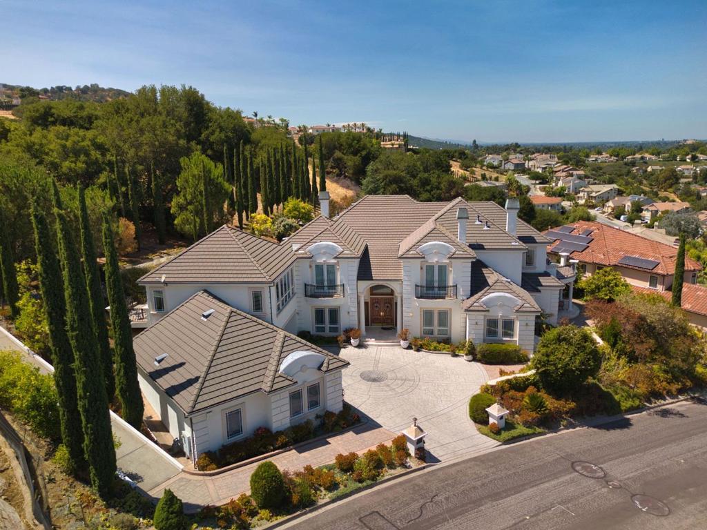 This magnificent property with exceptional craftsmanship in Almaden Valleys Country View Custom Estates offers elegance, versatility, and breathtaking views. The home features 4 bedrooms, 5 baths, a large bonus/media room, office, wine cellar, and dual two-car garages with workshop. One of the bedrooms is downstairs adjacent to a full bath, currently set up as a hobby and sewing room and can easily be converted back to a bedroom with the installation of a closet. A chef's kitchen with professional-grade appliances anchors the main level, while soaring ceilings, radiant heated floors, and 5 fireplaces add warmth and sophistication. The luxurious primary suite features dual balconies, a spa-like bath with triple shower and jet tub, and a private kitchenette. Extra insulation improves both energy efficiency and soundproofing, while the use of 2x6 framing offers superior strength compared to typical 2x4 construction. The home is fully equipped for networking, with six Wi-Fi access points perfect for today's connected lifestyle and seamless smart-home connectivity. Outdoors, tiered patios, a fully equipped Viking outdoor kitchen, gazebo, and wooden deck create a resort-style retreat framed by lush landscaping and fruit trees. Top Schools: Williams, Bret Harte and Leland High.