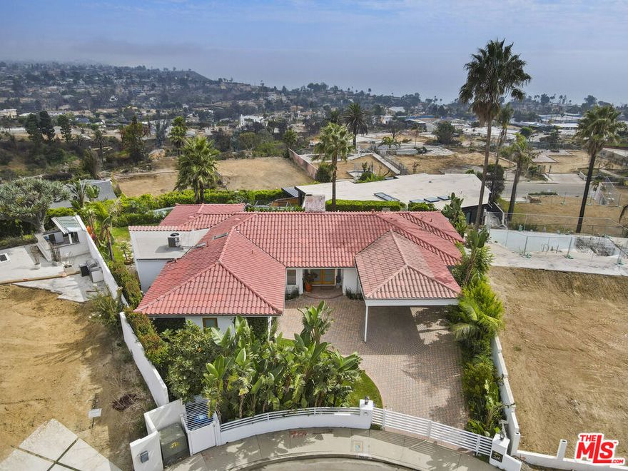 This incredible single-level modern Mediterranean showcases unobstructed 180-degree views of the ocean, coastline, Catalina, and shimmering city lights from nearly every room. Perched on a quiet cul-de-sac, the residence combines spectacular vistas with privacy, elegance, and a highly desirable layout. Set on approximately 9,800+ sq. ft. lot with an expansive 100-foot-wide backyard with a gorgeous pool and spa. The home spans approximately 2,900+ sq. ft. of living space. It features 4 bedrooms, 3.5 baths, plus a dedicated office space, also a large den with a wet bar. The interiors are appointed with gorgeous mahogany floors, a decorative working fireplace, redone bathrooms (one with steam shower), and a large gourmet kitchen with a dining area overlooking the yard and ocean beyond.The primary suite is a true retreat, offering breathtaking ocean views, a spacious walk-in closet, luxurious bathroom and direct access to the outdoors. The seamless indoor-outdoor flow extends to multiple entertaining spaces: a grassy yard, hardscaped patio, side yard with built-in BBQ for al fresco dining, and set against total privacy. Home is offered fully furnished, with some of the artwork included. This is a turn-key opportunity to enjoy the Palisades lifestyle immediately. Priced just above land value and sold in as-is condition, the property provides both present-day comfort and tremendous potential to reimagine to your own style. A truly unique residence where privacy, elegance, and some of the most captivating views in Los Angeles come together.
