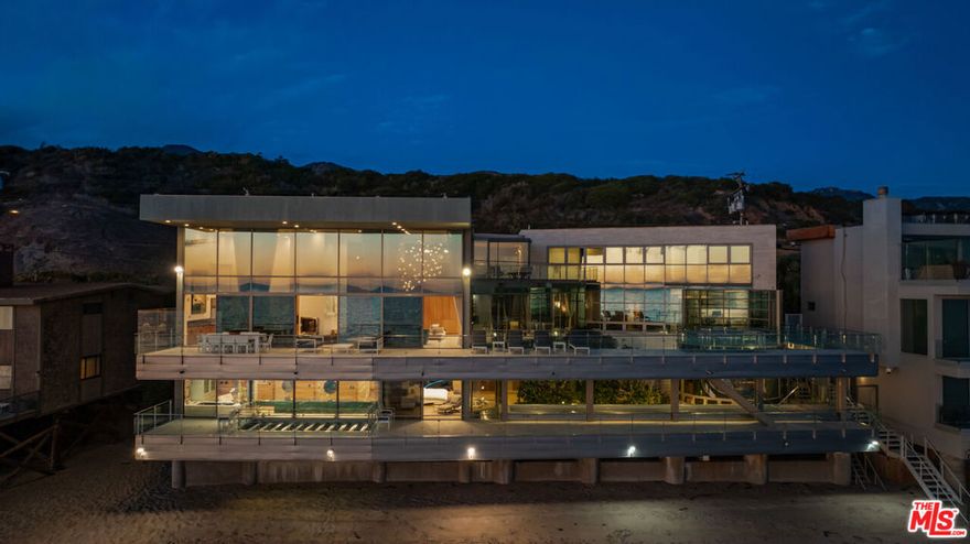 This exquisitely crafted residence is positioned upon an expansive double lot, boasting an impressive 128 feet of beach frontage. The residence is a marvel of architectural design, characterized by an open floor plan featuring lofty ceilings and expansive walls of glass that provide panoramic 180-degree vistas. The main level of this extraordinary abode encompasses a strikingly spacious master bedroom, occupying the entirety of the lower floor, along with three additional well-appointed bedrooms. An elevator facilitates convenient access throughout the residence, complemented by luxurious amenities such as a spa, extensive decks, and a distinctive round glass guest house. In addition to these remarkable features, the residence offers an indulgent Jacuzzi, a rejuvenating sauna, and an invigorating steam room. Furthermore, a fully-equipped gym adds to the comprehensive list of amenities, further enhancing the allure of this coastal masterpiece.