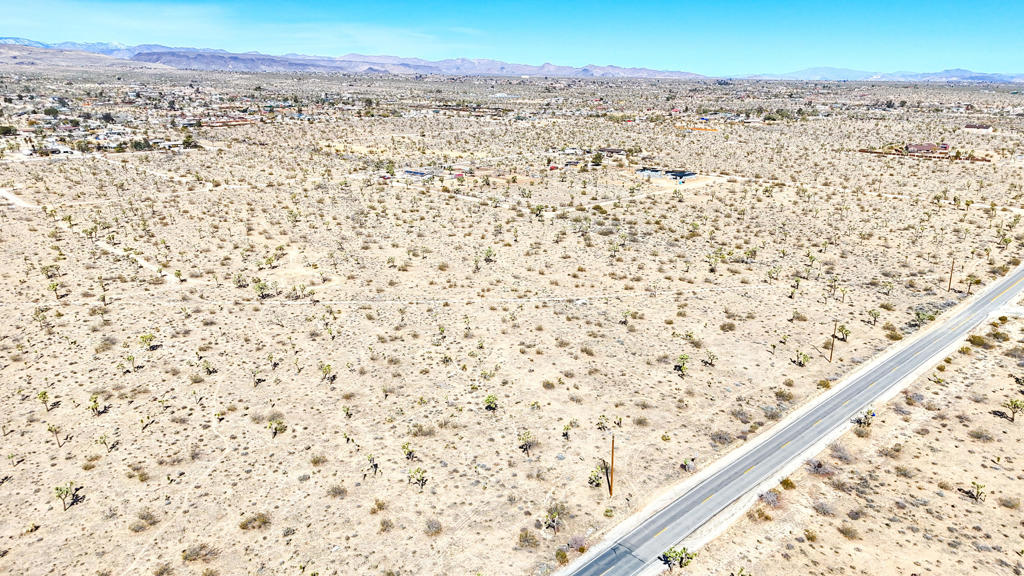 If you're looking for privacy, beauty, and room to create, this 5-acre lot is the perfect fit. Tucked just off Yucca Mesa Road, this parcel provides seclusion while remaining easily accessible. The flat terrain, adorned with native Joshua trees, offers a picturesque setting for a custom home, artist retreat, or vacation rental. Enjoy breathtaking sunrises, endless starry skies, and a tranquil atmosphere, all within minutes of the conveniences of Yucca Valley and Joshua Tree.With three adjacent 5-acre lots also available, this is your chance to expand your vision and build a grand 20-acre compound. Secure this one-of-a-kind property today and bring your desert dreams to life! Photo with red outline is all 4 parcels together. Other APNs available: 0598-084-31-0-000, 0598-084-32-0-000, 0598-084-33-0-000.