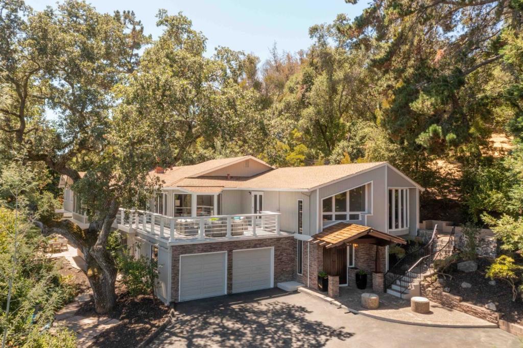 Tucked away on a secluded lot of nearly .70 AC in Sharon Heights, this spacious home offers over 5,600 SF of space in a serene, woodsy setting. Towering trees and foliage surround the home, which sits well back from the street on an extended driveway for added privacy. Soaring ceilings and abundant natural light create an airy ambiance throughout, while expansive gathering spaces include a large living room with a fireplace, a sunroom, a bar-equipped lower level, and a chef's kitchen with Sub-Zero and JennAir appliances. Four comfortable bedrooms include three with en suite baths, and the home also features an elevator, office, & outdoor spaces including a peaceful second-level terrace, a deck, and a patio ideal for relaxing or entertaining. All of this just moments from the Sharon Heights Golf & Country Club, scenic parks, shops, and restaurants, downtown Menlo Park, Sand Hill Road, and Interstate 280, with access to the acclaimed Las Lomitas school district (buyer to verify eligibility).
