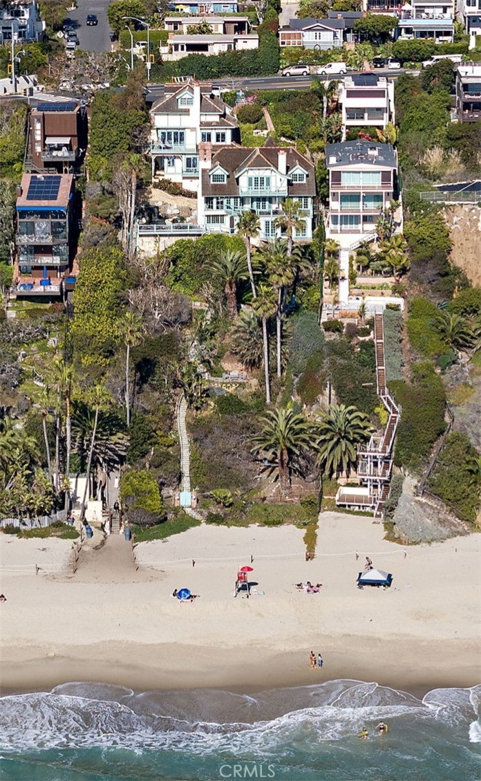 Welcome to "The Sea Castle", a stunning oceanfront compound offering panoramic views of the shoreline and Pacific. Spanning over half an acre, this enchanting property features direct beach access, lush grounds and a resort style pool and spa. This unique property consists of a primary residence expanded and redesigned in 1985, pool side guest quarters and a contemporary guest unit built in 1994. Stone garden pathways or a convenient funicular lead to the main residence. The Sea Castle is a masterpiece of craftsmanship highlighted by a stone turret, diamond patterned windows, and a distinctive shingled roof inspired by ocean waves. Inside, stone floors, an elegant floating staircase, and soaring beamed ceilings create a timeless ambiance. Natural lighting and picturesque ocean views immerse the living spaces. The grand living room exudes warmth with open beamed ceilings, a curved brick fireplace, clerestory windows and French doors opening to a spacious terrace. A formal dining room with handcrafted custom built-in provides an intimate setting for large gatherings, while the kitchen showcases inlaid wood cabinetry, a vintage Range, a dining nook and butlers alcove. The private primary suite offers an ocean view deck, fireplace, wet-bar, dual bathrooms and a walk in closet. Additional highlights include a large loft style office with built ins and ocean views, an inviting oversized family room with ocean views and 2 thoughtfully designed main level guest rooms. A private pool side guest quarters offers a living area with ocean views, a fireplace and sleeping area with ensuite bath. A separate second residence provides a contemporary coastal design with high ceilings, abundant natural light, 3 bedrooms (two ensuite), a den and ocean view patios. Outdoor spaces elevate the oceanfront lifestyle with multiple terraces, black-bottom pool and spa, and a pathway leading to the sandy paradise of Thousand Steps Beach where you can launch your sea kayak or paddleboard. The carriage house styled oversized three car garage features ample storage and an enviable motor court for additional off-street parking. Perfectly suited for multi-generational living, hosting guests, special events, or your very own private retreat. The Sea Castle Estate is a rare offering that captures the essence of the most coveted oceanfront living in Laguna Beach. A property of this caliber is seldom available. Experience the luxury, legacy and lifestyle of this one of a kind opportunity.