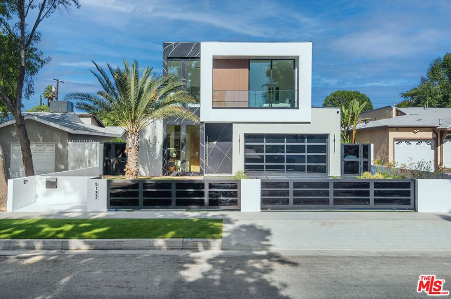 Wonderfully expansive contemporary home uniquely sited south of Ventura Boulevard, close to El Caballero Country Club in an enviable part of Encino. Two stories, with an architectural entry, 5132 Lindley Avenue boasts vast entertainment spaces, many with wood paneled walls and grand moonstone quartz that emulates the impressive exterior entrance. The living room is anchored with a custom-built floor-to-ceiling black and white fireplace, elegant paneling, and banks of modern bespoke doors offering backyard vistas to the pool and family room, a dining area, wine wall, and a beautifully appointed modern chef's kitchen with Miele appliances, 60" dual oven range and a generous marble pull-up waterfall island. This bright 5-bedroom, 6-bathroom home, completed in 2024, features a cohesive neutral color palette with unmatched quality throughout, including meticulous stonework, beaded wood panels, bespoke cabinetry, and large windows, complemented by wide-plank light oak flooring. All bathrooms feature intricate marble work and brass fixtures; the primary suite boasts a glass-fronted gas fireplace, marble shelving, a walk-in closet, and a stand-alone bathtub. A second ground-floor vocational space features a private additional living area. Oversized pocket doors lead to the outdoor heated pool and spa, and are surrounded by manicured gardens. Other amenities include wired speakers, a comprehensive security system, and WiFi extenders throughout the home, Apple iPad tablets to control home systems, and two AC units for optimal climate control.