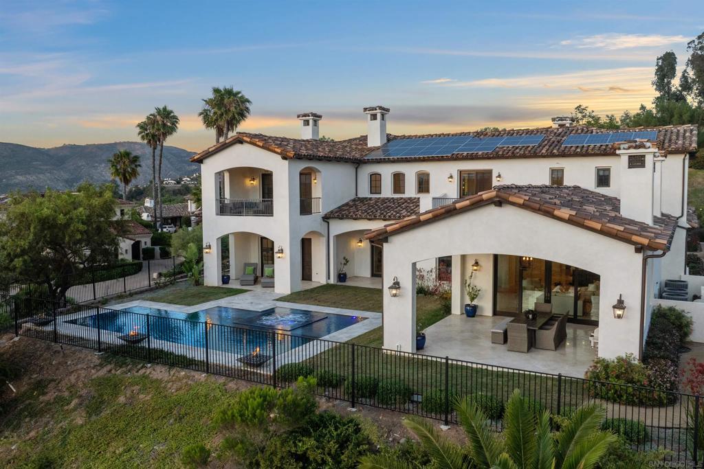 This absolutely stunning custom estate in The Crosby at Rancho Santa Fe was completed in 2022, making it one of the newest homes in this prestigious community! Designed by renowned local architect Scott Grunst, the home is situated on a quiet, beautiful street lined with luxury residences. The 6,523 sq. ft. residence offers timeless elegance and modern luxury. A grand 22-ft foyer welcomes you with soaring arched windows, hardwood floors, exposed solid wood beams, and a dramatic staircase with wrought iron railings. The chef’s kitchen features an eight burner Wolf range with an infrared charbroiler, 64" Electrolux fridge/freezer combo, and double Electrolux dishwashers, while the wet bar has a built-in kegerator. Wine lovers will appreciate the custom, temperature and humidity-controlled 800-bottle wine cellar with additional storage space. The house has Brazilian quartzite countertops and custom-built stained alder wood cabinetry throughout. Enjoy seamless indoor-outdoor living with disappearing pocket sliding doors that open the main living room to a covered loggia with full outdoor kitchen, fireplace, and Wolf BBQ. The resort-style backyard is very private and boasts a rim flow PebbleTec® coated pool, vanishing-edge spa, raised fire pits, and unobstructed sunset views over a protected natural preserve. No close neighbors ensure privacy and panoramic vistas. The home includes an elegant executive office downstairs with built-in bookcases and a fireplace, a massive upstairs primary suite, and a main-level guest/primary suite—perfect for multigenerational living. Upstairs you will find two additional ensuite bedrooms and a game room on the landing above the living room. Additional highlights include an owned solar system, oversized motor court, and a four-car garage setup: attached two-car garage with Tesla charger and detached two-car garage with added insulation and A/C wiring for yoga, gym, or studio use. The community is a quick 5-minute drive to Rancho Santa Fe Village through the north gate, while the south gate provides easy access to Hwy 56, Hwy 15, and Hwy 5 for convenient commutes, shopping, dining, and beach trips. Located within the top-rated Solana Santa Fe (K–8) and Torrey Pines High School districts, near premier private academies. Residents enjoy amenities such as a Fred Couples-designed golf course, 35,000 sq. ft. clubhouse, tennis and pickleball courts, Olympic size pool, spa, fitness center, fine dining, and vibrant social events.
