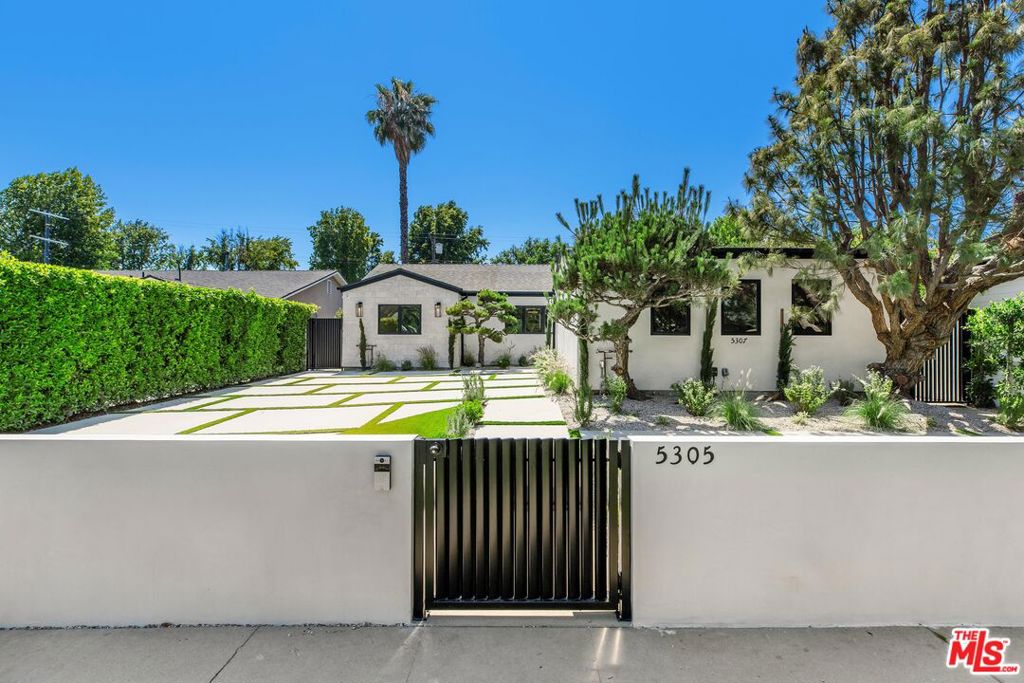 Situated on a tranquil street in the heart of Sherman Oaks, this stunning single-level residence has been thoughtfully reimagined with refined style and understated elegance. Featuring four bedrooms and three and a half bathrooms, the home showcases a generous open layout designed for both effortless living and elevated entertaining. At its center, a gourmet kitchen impresses with Fisher & Paykel appliances, sleek light-toned cabinetry, and an oversized island with bar seating, ideal for casual gatherings or everyday meals. The kitchen flows seamlessly into the living and dining areas, where a modern electric fireplace and pocket glass doors create a sophisticated connection to the backyard oasis. Down the main hallway are three bedrooms, including a serene primary suite featuring dual walk-in closets, direct access to the backyard, and a spa-like ensuite bath with a floating double vanity and expansive step-in shower with a built-in bench. A final bedroom is tucked away in the opposite wing of the home, featuring its own en-suite bath with a stone-topped vanity and luxurious step-in shower. A thoughtfully designed laundry area off of the bedroom completes the space with a deep sink, generous counter space, and additional storage. Designed for year-round enjoyment, the lush backyard embodies the best of California living with a built-in BBQ, sleek fire pit, and ample seating for gatherings under the stars. Ideally located moments from Westfield Fashion Square and the shops and restaurants of Ventura Boulevard, this turnkey home blends contemporary luxury with everyday convenience.