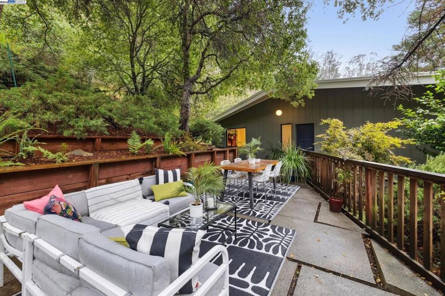 Surrounded by redwoods and beautiful oaks, this upgraded 3BD/2.5BA Mid-century home offers peaceful living in wonderful Montclair. The 1709 SQFT home welcomes you with a spacious terrace where you can unwind or entertain encircled by majestic trees and a terraced garden. Step inside the home’s open living area that compliments the setting’s natural beauty with a soaring beamed ceiling, a statement stone fireplace, and two sliding glass doors onto a new deck that spans the living and dining area. The adjacent stylish kitchen, the open floor plan, and wide deck offer seamless flow and indoor/outdoor living. New hardwood floors continue down the hall featuring a full bath with tub, one bedroom with a garden picture window, and a bright primary bedroom with an ensuite bath. Both bedrooms enjoy roomy closets and new recessed lighting. Downstairs find another private bedroom, half bath, laundry room, and indoor access to the oversized 2-car garage. Venture out the side door to relax or play on the newly refurbished back patio with pavers and raised garden beds. This wooded sanctuary is close to top-rated public schools, the Montclair Swim Club, and lively Montclair Village for shopping and dining; and East Bay Parks for recreation with miles of beautiful trails.