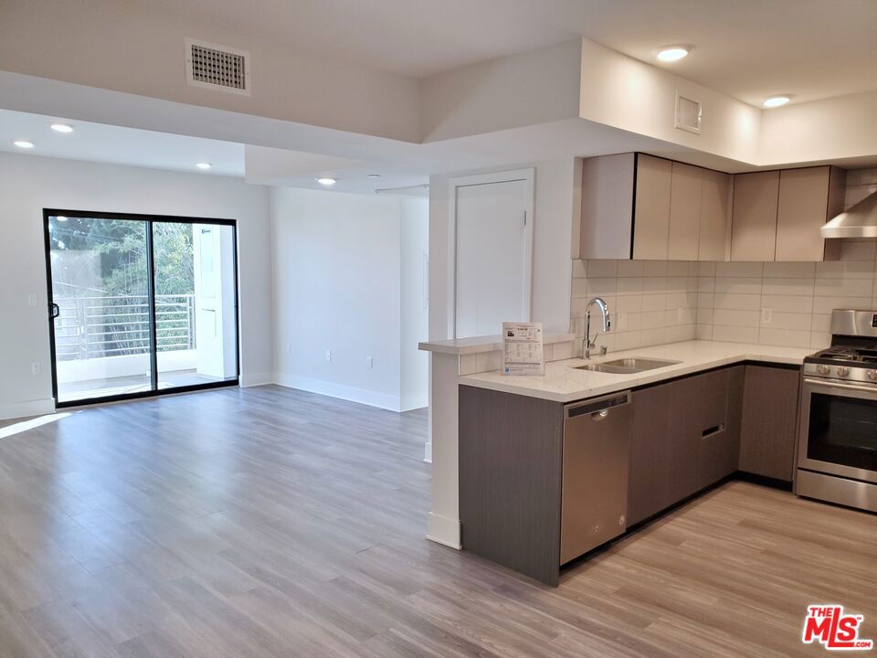 Top floor penthouse unit with balcony! This southwest corner unit has large windows in each room creating bright inviting spaces with views of downtown LA and hills. Open space floorplan with living room, dining area, and modern concept kitchen featuring stainless steel appliances, Caesarstone countertop and glass tile backsplashes. Primary bedroom with en suite bathroom and walk-in closet. Two additional bedrooms on the opposite side of the unit share a second full bathroom. Recessed lighting, beautiful flooring, hotel-like bathrooms, and washer/dryer in unit. Two tandem parking spaces in a secure gated garage. Small pets allowed. Convenient to Larchmont Village and Hollywood.