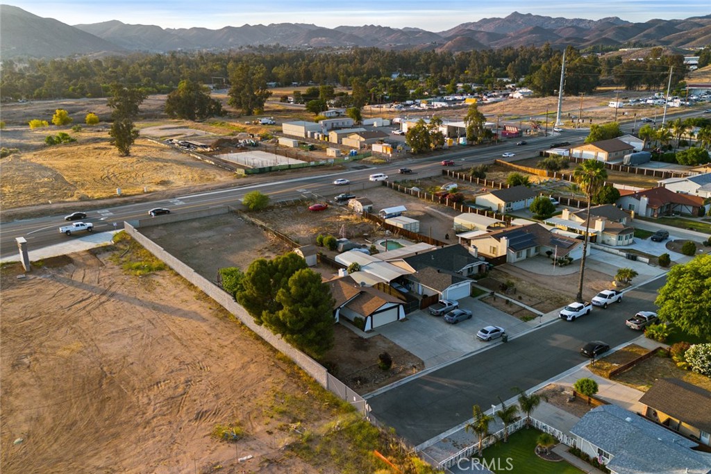 Welcome to your perfect blend of comfort, convenience, and character! This refreshed 3-bedroom, 2-bath home sits in a prime location just off the 15 Freeway—close to Costco, Walmart, the brand-new In-N-Out coming soon, and a Stater Bros. on the way. No need to drive deep inland to unwind—this home keeps you connected to everything while offering the privacy you crave. Inside, fresh paint, soaring ceilings, and exposed wood beams create an open, inviting atmosphere. A cozy fireplace anchors the living space, while the kitchen features durable Corian countertops. Some bedrooms have been upgraded with new double-paned windows for added comfort and energy savings, plus recent copper plumbing and a whole-home soft water system add peace of mind. A permitted bonus room with a wet bar sets the stage for entertaining, while the expansive, pool-sized backyard with a built-in fire pit is perfect for evenings under the stars. Sitting on just under a half-acre corner lot, this property has it all: RV parking, a large carport, a barn for storage or hobbies, a two-car garage, and a newly built block wall for privacy. With no HOA, low taxes, and endless potential to customize, this home checks all the boxes—space, convenience, and value. Whether you’re hosting friends, storing your toys, or simply enjoying your own private retreat, this property has everything you’ve been searching for.
