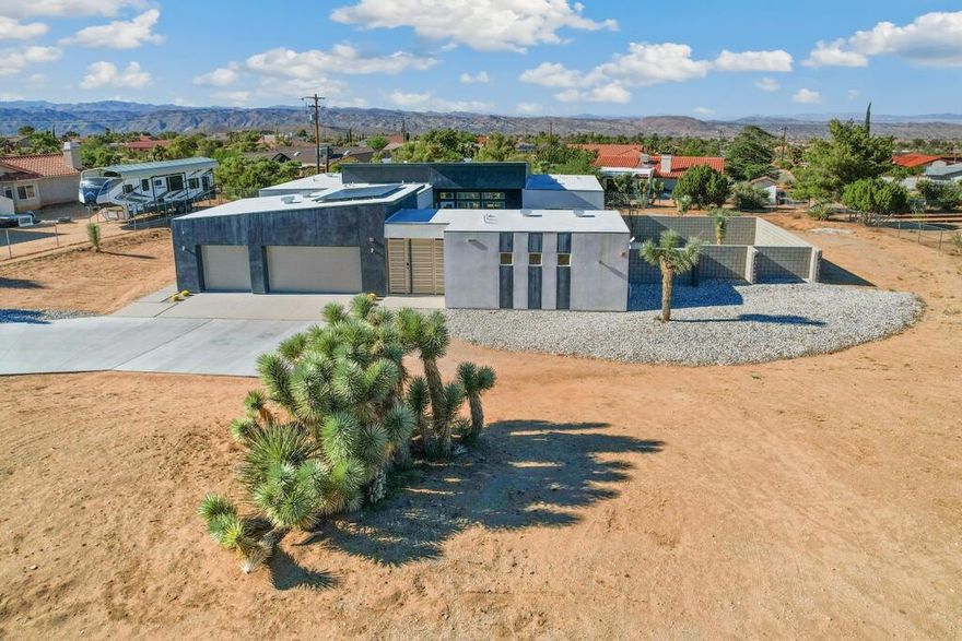 Enter into modern desert luxury with this custom home! This 4-bedroom, 4.5-bath home (including the private casita) blends style, comfort, and flexibility. Behind a custom gate, enjoy a spacious enclosed courtyard with multiple outdoor gathering areas--perfect for entertaining or relaxing under the desert skies. Inside, the dramatic open living room features soaring ceilings + designer finishes, and an entertainer's dream kitchen with a large quartz island and premium stainless steel appliances. Additional highlights include a 3-car garage, RV parking, and eco-conscious upgrades such as 10 paid solar panels and a tankless water heater. After a day exploring Joshua Tree National Park, unwind on your private courtyard patio while enjoying breathtaking sunsets. Ideal as a personal retreat or short-term rental, this home delivers modern luxury and desert living at its finest--don't miss this rare opportunity!
