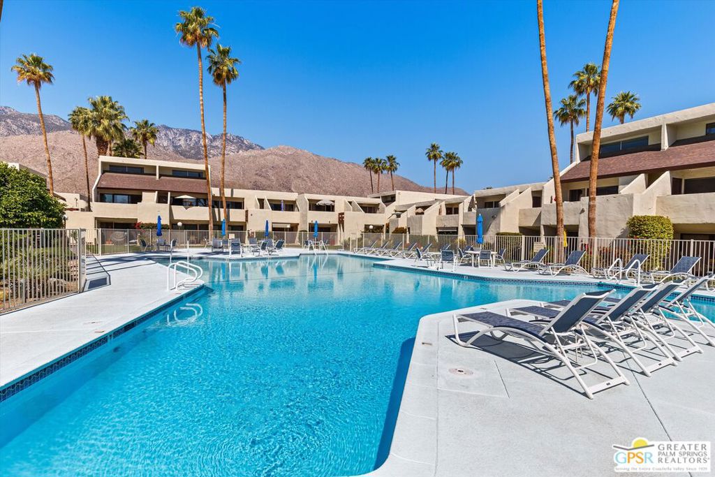 Welcoming spectacular mountain and resort views from inside and out, this impressively upgraded two-level condo offers a rare and coveted two-bedroom, two-bath floorplan at Palm Springs' Smoke Tree Racquet Club. Approximately 1,470 square feet, the open and extra-light residence features one bedroom on each level, ensuring maximum privacy and versatility. A spacious loft with wet bar, beverage refrigerator and stacked washer/dryer set can easily become a third bedroom, and the main-floor living room boasts a soaring ceiling, clerestory windows and access to a view-oriented patio. Granite countertops shine in both remodeled baths and the kitchen, which also features upgraded cabinetry, a peninsula and stainless steel appliances. Glass railings and acrylic handrails complement the staircase, and the condo offers tile flooring, carpet in the bedrooms, and a new energy-efficient HVAC system. Homeowners and their guests at Smoke Tree Racquet Club enjoy an exclusive resort-inspired setting that presents lighted tennis and pickleball courts, a dog park, and a beautifully landscaped central park area with lush lawns, an oversized spa, an extra-large pool and dramatic Mount San Jacinto views. Popular shops, restaurants, a Ralphs Supermarket and Ace Hardware are just across the street at Smoke Tree Village, and the cafes, clubs, galleries and boutiques of downtown Palm Springs are just minutes from home.