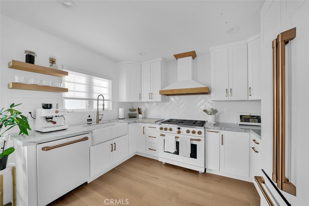 This recently remodeled single-family home is designed to meet the highest standards. Situated on a unique corner lot of approximately 2900 sq ft with new turf, it offers a serene setting in a quiet, family-friendly neighborhood. Begin your mornings with coffee on the porch,overlooking the picturesque bay view. The main living area features an open-concept design with a cozy fireplace, exuding a comfortable modern farmhouse vibe. The gourmet kitchen is a chef's dream, equipped with upscale Cafe' matte white appliances, custom design elements, a wine fridge, new windows and sliders,quartzite countertops,bespoke cabinetry,and waterproof Mohawk RevWood flooring throughout. The spacious dining area provides access to a private patio with peek-a-boo views of the bay. The first floor also includes a full bath and a separate laundry area for added convenience. Upstairs, you'll find three bedrooms, with the master suite offering an expansive balcony that showcases views of Marine Stadium and stunning sunsets. Two brand-new bathrooms upstairs exhibit designer elegance, catering to both the master suite and family needs. The property is equipped with brand-new air conditioning, updated electrical systems, motorized shades and more. The two-car garage includes a driveway for additional parking and features a 240-volt charging station for electric vehicles. Located in a peaceful neighborhood, this home offers a serene environment ideal for families. Enjoy leisurely strolls or bike rides around the bay, and take advantage of the proximity to shops, parks, and restaurants in Belmont Shore. Experience the perfect blend of modern farmhouse and contemporary amenities in thes beautifully renovated home.