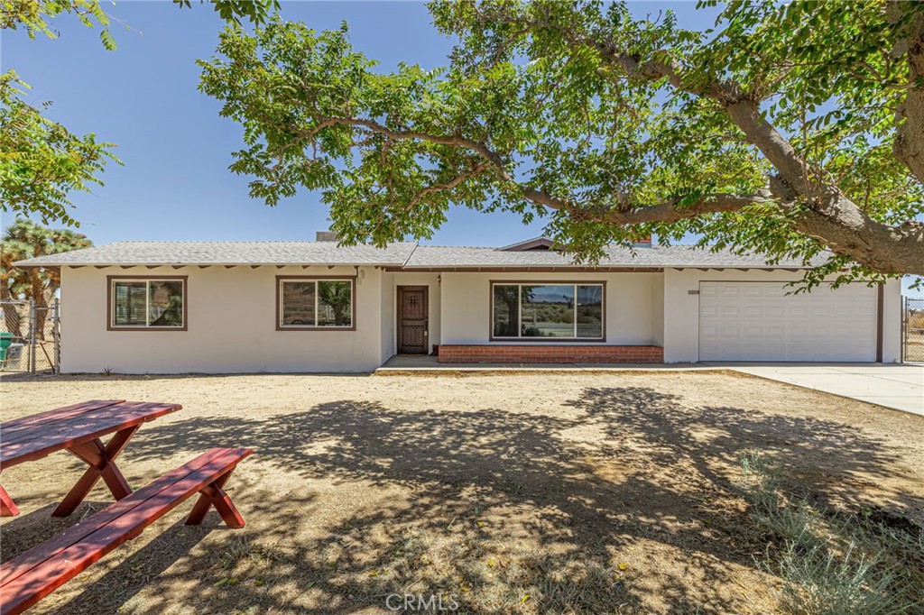 This charming three-bedroom, two-bath home, built in 1965, sits on a sprawling 2.35-acre desert oasis with its own well and septic system. Inside, enjoy new tile flooring throughout, newly painted interior and cabinets with Dunn Edwards paint, fresh carpet in cozy spaces, modern quartz countertops, striking copper-pounded sinks, ceiling fans, new window blinds, LED can lighting, Moen Posi-Temp shower valves, Installed new electric water heater. and a warm pellet stove—perfect for serene living and entertaining under starry skies. Rear yard secluded patio slab, RV hook ups available, carport, 40' aluminum insulated storage container and the lot is fully chain link fenced. Vinyl fencing at front entrance to shaded parking area. This home is move in ready.