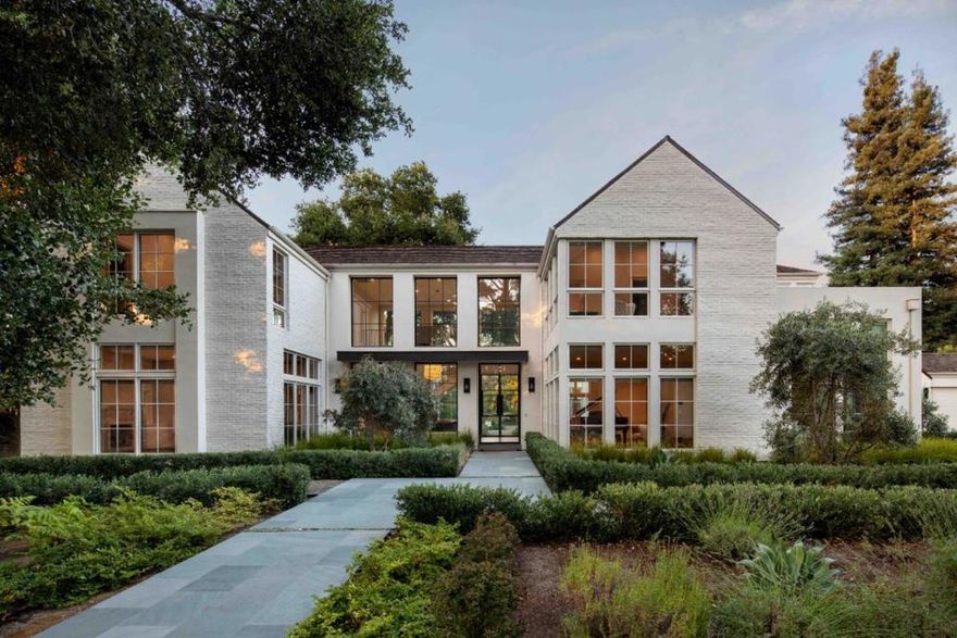 Completed in 2021, this contemporary estate pairs modern architecture with traditional reclaimed brick all in a soft white palette. Just over one acre of level grounds with two gated entrances frames the two-story home, which has 5 bedrooms, an office, and 5.5 baths, including an optional ADU with laundry and kitchenette ideal for an au pair or extended family. Beyond the formal venues, a main kitchen and professional chefs kitchen serve an open family room where disappearing glass doors create a seamless connection to the outdoors on two sides of the room. Four additional bedrooms are located upstairs, including the primary suite with sitting room and couture closet. The grounds are designed for entertaining with a pool, spa, and open-air cabana with full bath  all in a secluded, beautifully landscaped setting.