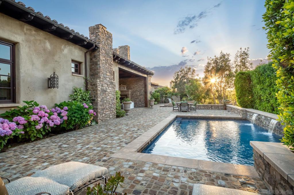 Offering an exquisite farmhouse on the west side of the Bridges at Rancho Santa Fe. Beautiful reclaimed wooden flooring, design details, unsurpassed finishes, including the kitchen with leather finish granite counters and custom Habersheim cabinetry. The entry doors welcome you into a generous foyer which leads to a Great Room boasting dramatic soaring ceilings, unique full indoor bar area and its own coffee niche. At every turn, you will be impressed with the rich appointments throughout. Primary en-suite offers two separate bathrooms and walk in closets. Upstairs bonus room would be a perfect movie theater or game room. Off the garage has a flex space for a workout gym.