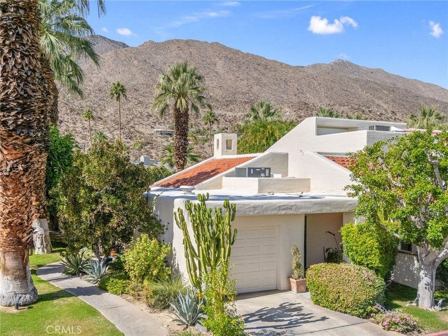 Discover this exceptional mid-century modern condo that offers the privacy and spacious feel of a single-family home. Situated in a gated community, this charming West-facing, end-unit, single-story home features brand new luxury vinyl floors, fresh paint throughout, and numerous upgrades including shutters, fridge, microwave, washer, dryer, and a brand-new water heater. In addition, there is no land lease providing long term value! The spacious living and dining areas feature stunning vaulted tongue-and-groove wood ceilings and a beautiful split marble fireplace, creating a light and airy ambiance complemented by breathtaking views of the San Jacinto Mountains. Step outside to the custom built front lanai; perfect for morning coffee surrounded by mature landscaped grounds. This home also offers custom shelving in the closets and garage, providing smart storage solutions. The back patio shares a yard with the neighboring unit and offers a private entrance to one of the pools. Resort-style amenities include two, tennis courts, pools and spas. Only one of several units to offer a convenient, attached one-car garage with direct access. Walk to downtown Palm Springs and enjoy the varied museums, unique shops, and incredible restaurants. Experience the perfect blend of classic mid-century design and elevated modern comfort in this beautifully maintained home. Don’t miss out on this chance to make it yours!