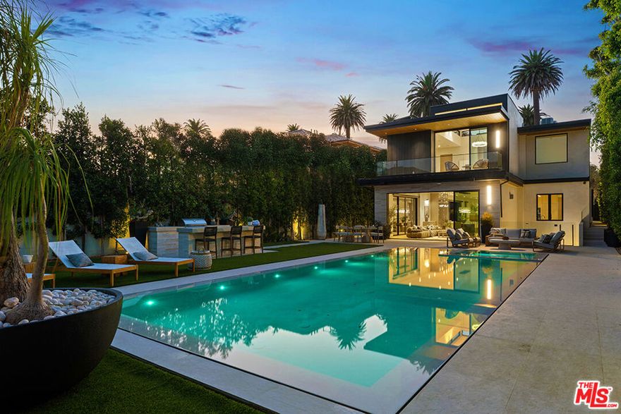 Set behind a canopy of mature olive trees that lend both shade and privacy, this newly built architectural residence spans approximately 7,700 square feet across two levels and a full basement. The main level unfolds with dramatic scale, offering expansive living, dining, and family rooms anchored by a sleek fireplace and framed by soaring floor-to-ceiling windows that flood the interiors with natural light. A flexible office or guest suite with an adjoining three-quarter bath enhances the layout. The gourmet kitchen is a statement in design, appointed with bespoke DOCA cabinetry, quartz countertops, a professional 6-burner cooktop with hood, Miele double ovens, wine refrigerator, beverage center, microwave, and a generous sized pantry. Upstairs, three spacious en-suite bedrooms include a tranquil primary suite featuring a fireplace, private balcony, custom oversized closet, dual sinks, freestanding soaking tub, and a luxurious rain shower. A serene hallway patio and a second laundry room add both style and convenience. The lower level is dedicated to leisure and wellness, boasting a state-of-the-art theater, fitness studio, wet bar, sauna, steam shower, bedroom with en-suite bath, custom built-ins, and a refined fireplace. Outdoors, the resort-style backyard is designed for entertaining with a sparkling pool and spa, barbecue island, mini-fridge, and a two-car garage. A private junior ADU suite offers further versatility with a kitchenette, stacked washer/dryer, three-quarter bath, balcony, and dramatic floor-to-ceiling windows. Additional highlights include wide-plank hardwood and stone flooring throughout, elevator access to all levels, and a fully integrated Crestron smart home system. Located on one of Santa Monica s most desirable streets, just moments from Palisades Park, the beach, fine dining, and luxury shopping.