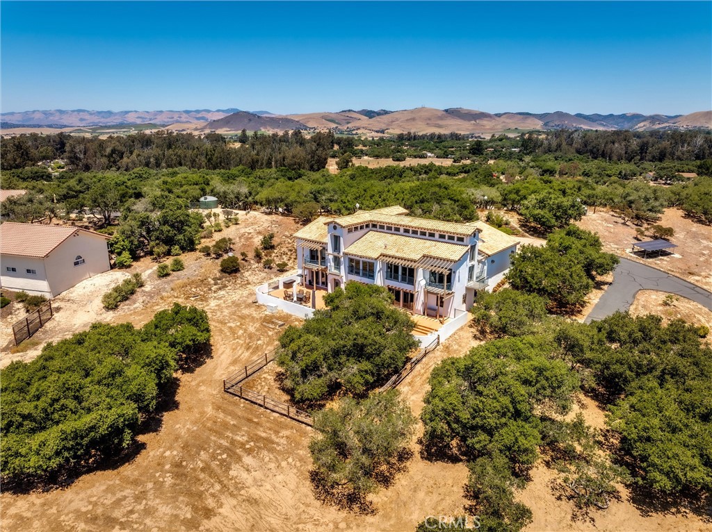 Perched atop the Arroyo Grande Mesa in the exclusive gated community of Black Lake Ranch Estates, this exquisite Spanish-style home offers the perfect blend of elegance, privacy, and panoramic beauty. Set on 2.75 acres, this custom-built 5-bedroom, 4-bathroom residence spans 4,598 square feet and showcases sweeping views of the Pacific Ocean, oak-studded hills, and the iconic Pismo Dunes. This community has a total of 17 homes.
The main floor features a great room, kitchen, formal dining area, powder room, spacious primary suite, and a guest room currently used as an office. Designed with sophistication and warmth, the home boasts soaring clerestory ceilings, sweeping archways, oversized windows, and a harmonious mix of natural materials—Saltillo tile floors, granite countertops, exposed wood beams, and rich cherry wood finishes.
The expansive primary suite offers a true sanctuary, complete with vaulted ceilings, lovely balconies, abundant natural light, a spa-inspired bathroom with dual sinks, oversized tub, separate shower, private toilette room and a generous walk-in closet.
A dramatic stairway leads to the lower level, where you’ll find a spacious media room with surround sound, a wet bar, and three additional bedrooms, two full bathrooms, a sauna, and a versatile bonus room currently being used as a gym. Step outside to a beautifully designed patio with an outdoor kitchen and a private area with a concrete pad—ideal for your future hot tub.
Additional highlights include an oversized 3-car garage, separate golf cart garage, RV parking, and ample storage. Ideally located just minutes from the charming Village of Arroyo Grande, the beaches of Pismo, and the vibrant city of San Luis Obispo, this exceptional property offers the serenity of a private retreat with the convenience of Central Coast living. 1790 Calle Laguna—where luxury, comfort, and California’s natural beauty come together.