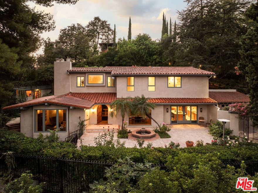 Rising behind bougainvillea-draped gates, 333 N San Rafael is a Mediterranean home in Pasadena's San Rafael Hills, transformed through a three-year renovation by Tatum Kendrick Design that layers historic charm with intentional, contemporary detail. A brick and stone front courtyard introduces interiors anchored by original parquet flooring and arched passageways, creating a sense of rhythm and continuity throughout. Limewashed-plaster walls, custom oak millwork, and carefully selected lighting enrich the palette. The living room, featuring painted beams and a custom fireplace, blends vintage character with comfort, while the dining room is framed by a curved window and sculptural brass chandelier, an inviting backdrop for gatherings. A den, media lounge, and library-style workroom extend the home's versatility, offering distinct areas for daily living and entertaining. At the center of the house, the kitchen was conceived as the heart of the home. A burl-wood island with integrated brass sink anchors the space, complemented by walnut cabinetry, marble counters, a built-in coffee bar with reverse osmosis water filter, dual walk-in pantries, and a full suite of custom storage. The AGA induction range pairs with a concealed Monogram hood and Waterworks fixtures, while a curved breakfast nook with custom banquette seating creates a cozy place to begin and end the day.Upstairs, the bedrooms carry the same level of detail. The primary suite features a fireplace and an abundance of natural light, accompanied by an en-suite bath that offers a steam shower with dual shower heads, marble accents, dual vanities, and towel warmers. Secondary bedrooms are equally considered, with custom hardware, artisan tile, and thoughtfully layered lighting. Throughout, details such as a powder room wrapped in Zak + Fox wallpaper with a Calacatta Viola marble sink, a lilac marble bar, a fully appointed laundry designed with equal attention to storage and finish, and a custom plaster handrail elevate the everyday. Outdoors, the property unfolds as a series of intimate and expansive moments. Courtyards, patios, and multi-layered stone paths wind through lush landscaping including citrus trees, leading to spaces for alfresco dining and entertaining beneath trellised greenery. A spa is tucked into the garden for evenings under the stars, while a separate structure offers flexibility for an art studio, gym, or additional office. Every angle reveals a sense of discovery, creating an atmosphere that feels both private and enchanting. Positioned in the sought-after San Rafael neighborhood, the home enjoys hillside seclusion with views of Downtown Pasadena while being moments from the Rose Bowl, Old Town Pasadena, and the neighborhood's cultural landmarks.