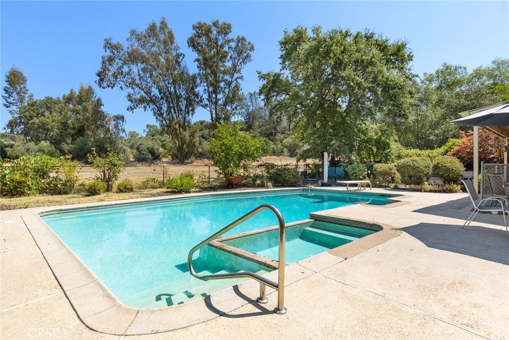 SELLER OFFERING BUYER $6K Closing credit to help with closing costs or perhaps buy down interest rates. Because the 7.3 kw OWNED SOLAR is paid off, the PG&E true-up bill was only $751.00 for the ENTIRE YEAR in 2024! Beautiful house with all the wish list items: Cul-de-sac, 1.33 acres, POOL, HORSE PASTURE, REMODELED High-end Kitchen (sellers were planning for this to be their forever home and spared no expense on custom cabinets, quartzite counters, farm sink and walk-in pantry with office desk and window and a new half bath). Newer Engineered hardwood in kitchen and entry and hall. WOODSTOVES in both living rooms with custom rock hearths. HUGE, detached GARAGE with air-conditioned office/ 4th guest room that has ADU/ mother-in-law unit potential, workshop with wood stove, tack room, hay shed, fenced and cross fenced. Very quiet and private yet moments to shopping and walking distance to school. OUT-DOOR KITCHEN on large covered fenced patio, various sheds and dog runs, and garden areas with established landscaping. Tons of room to park RVs, BOATS, HORSE TRAILERS. Primary bedroom has remodeled bathroom with low threshold custom stone and tile shower and HEATED FLOORS. Glass doors from primary bedroom lead to the pool and offer views of the covered patio, pool, horse pasture and lush olive groves. Wheelchair ramp to front door and paved parking in front. Second living room has its own entrance and beautiful exposed antique beams with adze marks and tons of natural light and cozy window seats with storage benches. Spanish tile roof and custom brick work make this the perfect blend of county ranchette and cozy home with luxury upgrades and potential for second unit--on Sewer, not septic, which makes additions much easier. In-ground gunite pool was resurfaced about 6 years ago and has an outdoor bathroom and lots of storage for pool floaties and equipment. Security fence separates it from the outdoor kitchen for added water safety. Woodstoves add charm and warmth. House also has a newer central heat and air system installed in 2013. Solar Installed in 2019 and is included with sale with $0 owned. Potential to rent out pasture to horses for supplemental income.