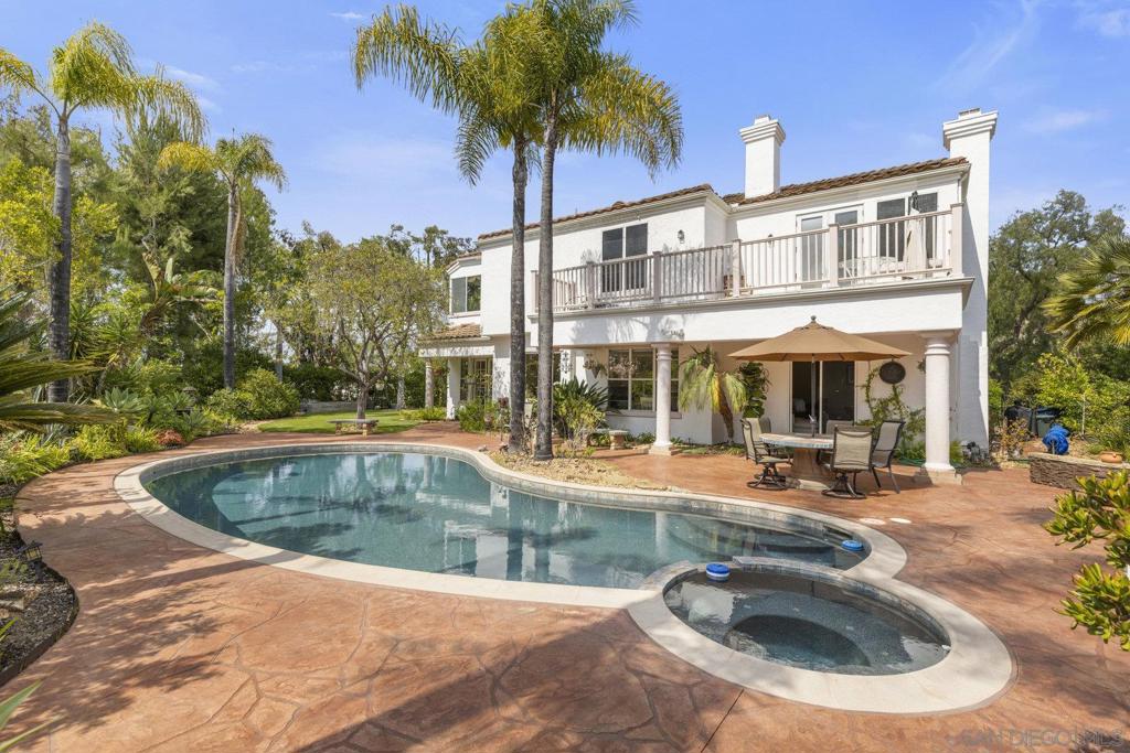 Discover this beautifully appointed home in the gated community of Queensgate, set on a private ½-acre lot with stunning mountain views. Elevated above the neighborhood, the property feels like a secluded retreat, complete with a Pebble Tec pool and spa, resurfaced pool decking, and a built-in outdoor BBQ island for effortless entertaining. Inside, soaring cathedral ceilings and tall windows fill the living space with natural light. Travertine floors flow throughout the downstairs, where you’ll also find a full bath and a flexible billiards room that could easily be converted back to a bedroom with ensuite. The kitchen is a true chef’s delight, featuring brand-new Thermador and KitchenAid appliances, granite countertops, a large center island, and views of the backyard oasis. Upstairs, the expansive primary suite offers warm wood flooring, a private retreat, and a spacious balcony with sweeping west-facing mountain views. The remodeled primary bath feels like a spa, with luxurious travertine, a walk-in shower, a jetted tub overlooking the treetops, and a generous vanity. Additional highlights include a Jack-and-Jill bathroom between two upstairs bedrooms, a private bath for the guest suite, a side yard with high-end synthetic turf, and a peaceful, quiet setting just minutes from revitalized Downtown Escondido, Rancho Santa Fe, and the 15 freeway.