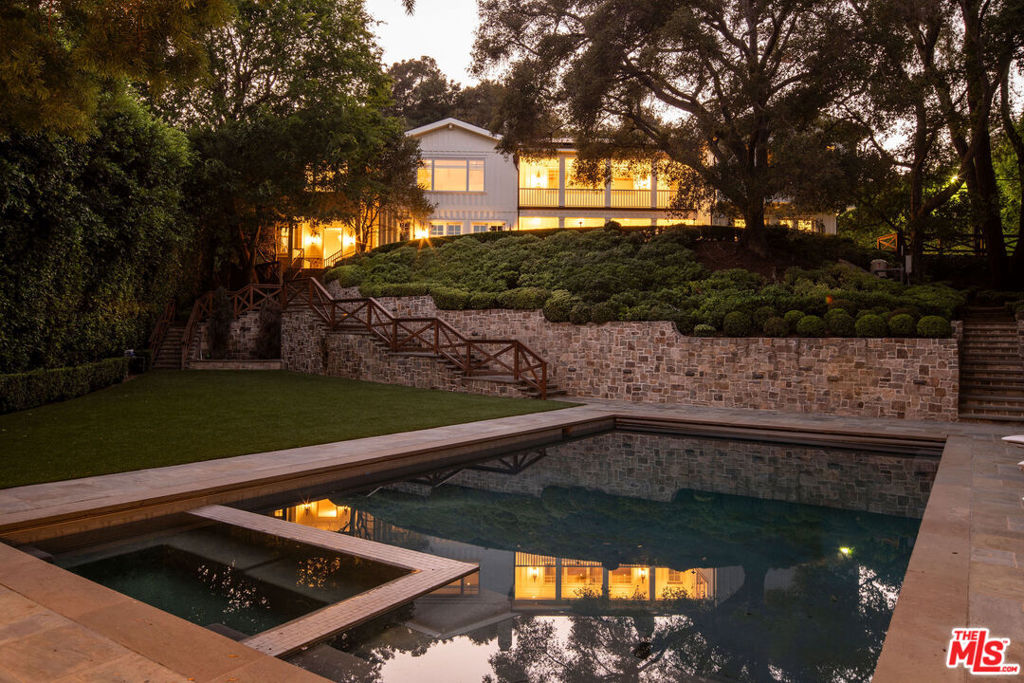 Step behind a discreet gate into a private oasis. A gentle stream sets a calming tone as views open to nearly an acre of park-like grounds. Stone pathways lead to beautiful yards for relaxation and play, a sports court, a gorgeous pool area with spa and guest house. The main residence, reimagined with Maurice Gadson Design, embodies simplicity, beauty, and craftsmanship. The dramatic living room and kitchen with soaring ceilings and seamless garden access are the heart of the home. The custom wood paneled media room and secondary family room were designed for comfort and flexible living. Every detail speaks of curation: Samuel Heath and Waterworks fixtures, vintage French lighting, textiles by Holly Hunt, Thomas Lavin, Schumacher, Missoni runners, Calcutta stone, custom millwork, and Christian Lacroix wallpaper. Smart automation and tailored shades complete the experience. The outdoor kitchen and dining area with views of your very own vineyard elevate one's entertaining experience and evenings by the outdoor fireplace brings birdsong, owl calls, and absolute tranquility. Boca de Canon is a setting that truly cannot be replicated.
