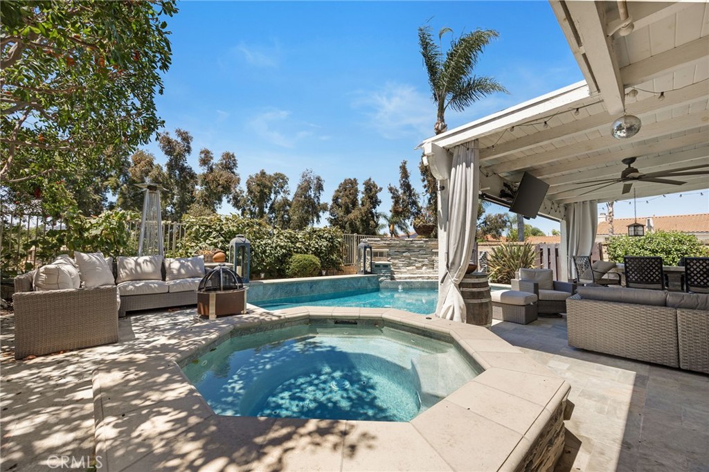 Welcome to this elegant five-bedroom, three-bath residence, offering approximately 2,600 square feet of refined living space designed for both comfort and sophistication. From the moment you enter, you’re greeted by an impressive formal living and dining area with soaring two-story ceilings, expansive windows, and an abundance of natural light that accentuates the home’s timeless architectural appeal. A warm and inviting family room with a custom built-in media center and fireplace provides a seamless blend of elegance and relaxation and the perfect space for casual evenings or intimate gatherings. The gourmet kitchen is a true centerpiece of the home, crafted for the culinary enthusiast with premium stainless steel appliances including a double oven, one with french doors, an apron sink, cooktop, dishwasher, microwave, refrigerator, and massive 120 bottle Viking wine refrigerator. Custom cabinetry, a full granite backsplash, and an oversized walk-in pantry elevate both form and function. A charming breakfast nook completes this exceptional space, offering the perfect spot to start your day. A private downstairs bedroom and full bath create a flexible layout ideal for guests or multi-generational living. Upstairs, the luxurious primary suite is a serene oversized retreat, spa-inspired en suite bath with dual sinks, an oversized travertine shower, and a striking standalone copper soaking tub — a true statement of artistry and relaxation. Three additional large secondary bedrooms offer comfort and style for family or guests with a full bath to share. The resort-inspired backyard is an entertainer’s dream, showcasing a sparkling resort style pool with a separate spa and tranquil waterfall feature. A covered patio with an outdoor kitchen, built-in barbecue, and generous lounging space makes hosting effortless and elegant. Additional highlights include an indoor laundry room, a three-car garage with ample storage, and an extended driveway for extra parking. The property enjoys direct access to a scenic park and is ideally positioned near premier shopping, dining, and convenient freeway access. This exceptional residence blends sophisticated design with everyday livability — offering the perfect balance of luxury, privacy, and convenience. A true sanctuary that embodies the best of California living.
