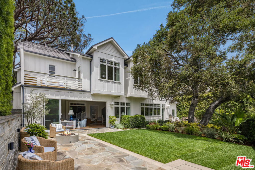 Designed by Gray Malin, renowned fine art photographer, this beautiful home exudes sophistication with a refined coastal elegance. Ideally located in Rustic Canyon, a prestigious enclave by the Pacific Ocean. The gated front courtyard features whimsical hedging, combining with mature trees and lush greenery for dramatic curb-appeal. Upon entry guests experience a double-height ceiling and voluminous rooms blending open-concept living with defined spaces. A formal entry, sitting room, office or den, and a refined dining room pivot around the stately oak spindle staircase. The living room with wood beamed ceiling, central fireplace and fully retractable wall of glass creates the optimal Southern California indoor-outdoor experience. The main level further includes a secondary dining area, top of the line chef's kitchen featuring Sub-Zero and Wolf appliances with custom cabinetry and large island, dual dishwashers, a walk-in pantry, butler pantry with wine fridge, an office area, secondary entrance/mudroom and half bath. The second level is graced by an oversized primary suite with vaulted ceilings, fireplace, walk-out patio overlooking the lush backyard and canyon views, double walk-in closets, a beverage area and resort-like spa bath with heated stone flooring, soaking tub and steam shower. Three guest rooms, a flex-space perfect for a family room, children's playroom, additional office or bedroom, three baths, and laundry complete the upper floor. At the lower level a generous entertainment room with state of the art movie screen, projector and surround sound, a secondary kitchenette/bar, a full home gym and additional bathroom create the ultimate entertainment retreat. A beautiful mature oak tree defines the natural setting of the backyard with outdoor sitting areas with fire pit, a spa-pool with fountain, built-in bbq and alfresco dining area perfect for relaxation, play or entertaining guests. It offers the ultimate privacy with beautiful canyon views, a collage of greenery with citrus trees, hedges, a variety of flowers and raised garden boxes for harvesting farmed vegetables. The property features wide-plank oak floors and coastal designer details throughout with a 2-car garage, solar panels (with capacity to install Tesla Powerwall), EV charging, PuroServe home water filtration system and a storage room. With close proximity to nearby Rustic Canyon Park with tennis courts, top-rated Canyon Charter School, and fine dining establishments Giorgio Baldi, Muse, the historic Golden Bull, Cafe Delfini, Rustic Coffee and Shore Bar. The home is matched for the most discerning clientele and can be purchased fully-furnished, turn-key ready for occupancy.