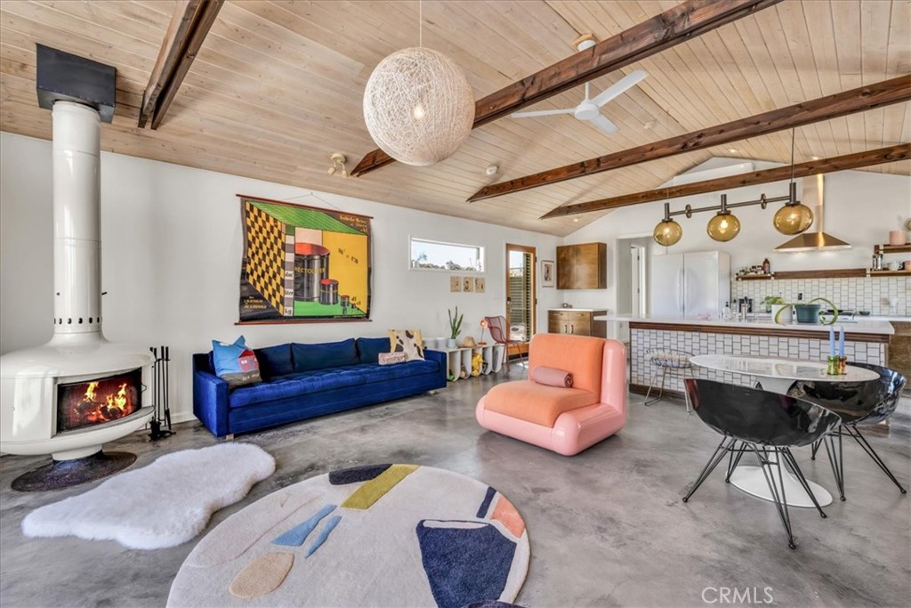 Tucked away in the iconic Pipes Canyon area of Pioneertown, this beautifully remodeled home sits on 1.24 acres and is surrounded by natural beauty, overlooking 168 acres of Wildlands Conservancy land to the south—offering endless views and easy access to hiking. Thoughtfully updated, the home features vaulted tongue-and-groove ceilings and a striking mix of custom industrial and designer finishes throughout. The living area is anchored by the French doors and large windows with unspoiled south-facing views of surrounding mesas and a vintage Malm wood-stove, while the kitchen boasts a custom lighting installation over the island, high end appliances and stylish tile backsplash. New mini-splits provide efficient climate control, and dimmers on all lights let you set the perfect mood. The primary bedroom fits a king bed with room to spare and includes a large walk-in closet, while the second bedroom comfortably fits a queen. The clawfoot soaking tub, outdoor shower, cowboy tub, and hot tub invite you to slow down and embrace desert living at its finest. The exterior of the home is clad in smooth stucco and corrugated metal siding, combining durability with a sleek aesthetic. A new solar system (installed just one year ago) provides a surplus of energy and will be paid off at closing, while a private well supplies the water. Think of the landscaping possibilities with no water bill! A detached wood exterior structure with power and water creates filtered light and privacy around the cowboy tub and outdoor dining area. Located on a county-maintained road, just minutes from the shops and restaurants of Pioneertown—including the legendary Pappy & Harriet’s and Red Dog Saloon—and only 20 minutes to downtown Joshua Tree, this stylish desert home is the perfect blend of design, privacy, and prime location. Welcome to your high desert hideaway.