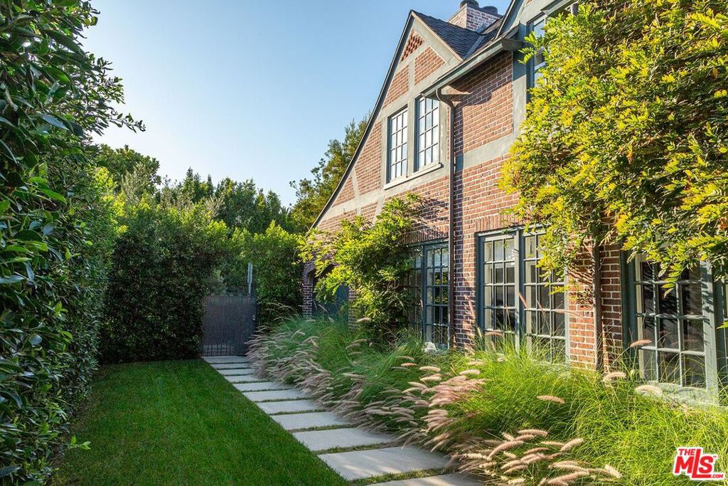 Your Dreamy Country English Retreat in Windsor Square. Tucked away on one of Windsor Square's most coveted and idyllic blocks affectionately known as "Little Bronson" this enchanting Country English residence offers the perfect blend of charm, privacy, and modern luxury. Step behind the gate and hedged gardens to a path that leads to the front door. Inside, sun-filled rooms and timeless details create a warm sense of welcome. The spacious living room, anchored by a fireplace and walls of windows, opens through French doors to a romantic courtyard ideal for entertaining or quiet evenings under the stars. A formal dining room flows seamlessly to the rear gardens and sparkling pool, while the chef's kitchen, complete with center island, high-end appliances, and a walk-in pantry, is designed for both beauty and function. For moments of retreat, the cozy library invites you to settle in with a favorite book. The first floor also includes a stylish powder room, guest bedroom/office, and full bath. Upstairs, the primary suite is a private sanctuary with its own fireplace, spa-like bath, generous walk-in closet, and serene treetop views. Three additional bedrooms, two impeccably designed bathrooms, and a versatile den/playroom/office complete the second floor. Outdoors, discover thoughtfully designed spaces for every mood and occasion from the secluded inner courtyard, to the sun-drenched pool, to the inviting fire-pit perfect for cool summer nights. Every detail of this home reflects meticulous design and care, creating a truly magical retreat you'll never want to leave.