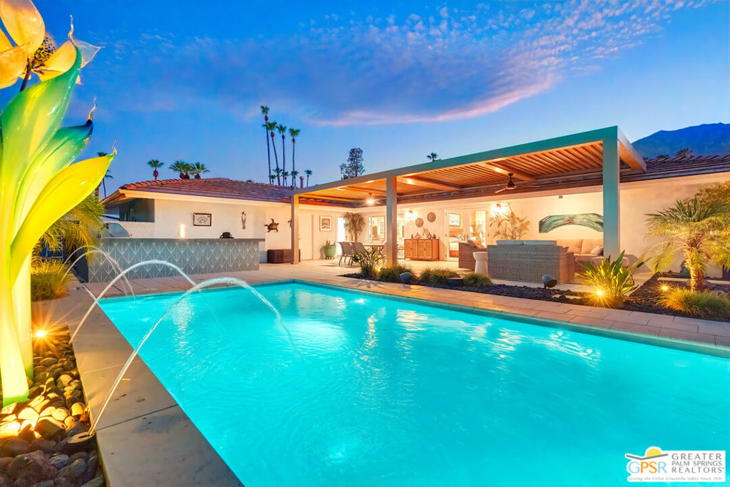 Beautifully reimagined in the heart of South Palm Springs' sought-after Deepwell neighborhood, this three bedroom, three bath home blends refined modern design with exceptional outdoor living. Surrounded by boulders, mature Palms, Yucca, and Olive trees, the illuminated landscape sets a dramatic tone from the moment you arrive. The front yard offers a basalt three-column water fountain, stone seating, and a firepit for quiet evenings under the stars. Inside, high-gloss 24"x24" ceramic tile floors lead into an open-concept living space with lovely Mt. San Jacinto views. The gourmet kitchen boasts Quartz countertops, custom backsplash, espresso cabinetry, and stainless Jenn-Air appliances all centered around a sit-down bar perfect for entertaining. All baths feature large walk-in showers and modern finishes. The primary suite opens to a resort-style backyard with a deepened pool, cascading deck fountains and waterfalls, an elevated firepit lounge, and an alfresco BBQ kitchen. The high-tech louvred patio cover responds automatically to wind and rain, and an outdoor shower adds convenience. Energy-efficient with a fully owned solar system and backup battery, LED lighting, Nest thermostat, and low-maintenance desert landscaping. A rare blend of luxury, function, and location. Palm Springs living at its finest.