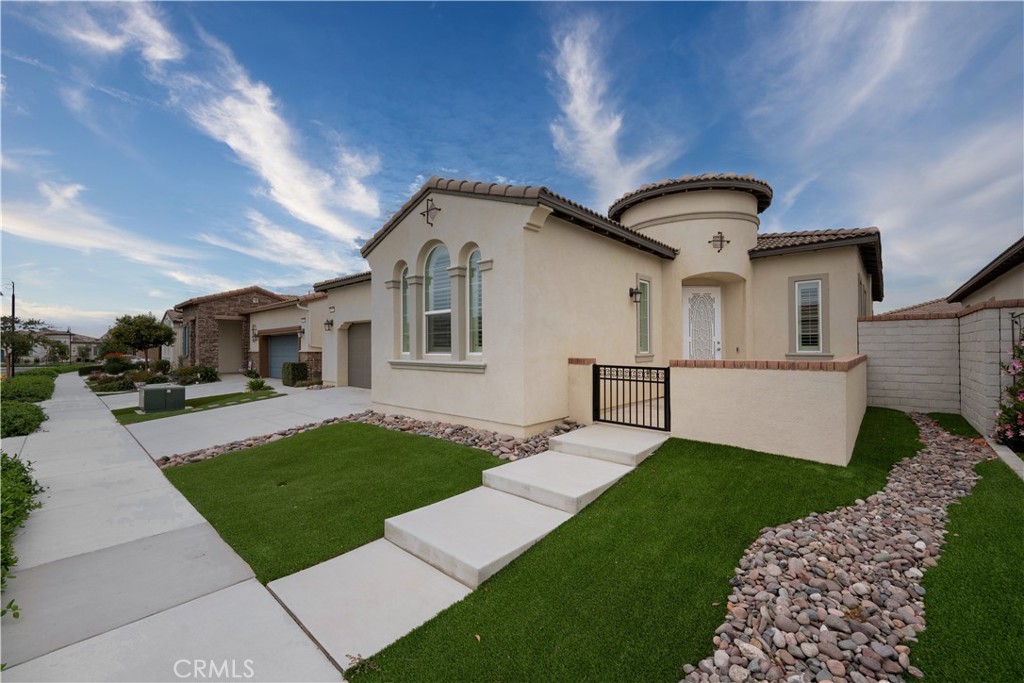 Welcome to resort-style living in the heart of Ontario Ranch! This beautifully upgraded home, located in the exclusive gated Esperanza 55+ community, offers over 1,800 SF of thoughtfully designed space perfect for comfort, entertaining, and everyday ease. From the moment you arrive, the beautiful curb appeal invites you in, low maintenance landscaping, sets the tone for effortless living. Inside, you'll find soaring 9-foot ceilings, luxury vinyl flooring throughout, and an abundance of natural light thanks to oversized windows with custom shutters. The heart of the home is the chef’s kitchen featuring a massive center island, stainless steel appliances, and sleek cabinetry ideal for gatherings with friends and family. The open concept layout flows seamlessly into the living and dining areas, while a versatile flex room offers the perfect space for a home office, craft room, or potential third bedroom. The spacious primary suite includes dual vanities, an oversized spa-style shower, and a generous walk-in closet. A secondary bedroom, large laundry room, and built-in cabinetry add even more function to the floor-plan. Step in the backyard and experience tranquity with the covered patio, landscaped yard, and mountain views. As a resident of Esperanza, enjoy access to the resort-inspired La Jolla Clubhouse featuring a fitness center, pickleball court, pool, bar, outdoor kitchen with BBQ, fire pits, and even a dog park. This home is the perfect blend of modern luxury and low-maintenance living designed for those who want to live life to the fullest in a vibrant, active adult community. Schedule your showing today, and see all this home and community has to offer!