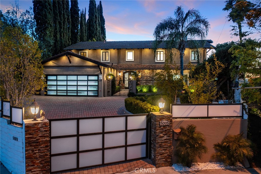 Luxurious Vista De Oro Estate – Gated, Private, and Unparalleled Views! Tucked away at the end of a quiet cul-de-sac south of Ventura Blvd, this stunning Woodland Hills residence offers privacy, sophistication, and panoramic views on a sprawling 16,000+ sq ft lot. With 5 bedrooms, 3.5 bathrooms, and over 3,800 sq ft of thoughtfully designed living space, this home is perfect for both entertaining and everyday comfort.Step through grand double doors into a dramatic entry with soaring ceilings, a show-stopping chandelier, and a sweeping staircase. Natural light fills the home, accentuating the elegant finishes and breathtaking valley views. The main floor includes a versatile bedroom (currently used as an office) with access to a full bathroom and the attached garage—currently converted into a stylish man cave. The spacious family room features built-ins, large picture windows, and a double-sided fireplace that opens to the formal living room, creating a warm and welcoming flow. The formal dining room is perfectly positioned to enjoy the stunning backdrop. The updated chef’s kitchen is a showpiece, complete with custom white cabinetry, quartz countertops, a large center island, top-of-the-line stainless steel appliances—including a 6-burner Wolf range—and walls of windows framing the gorgeous scenery. A separate laundry room is conveniently located just off the kitchen. Upstairs, the expansive primary suite offers a true retreat with a cozy fireplace, dual walk-in closets, and a spa-inspired en suite bathroom with soaking tub, dual vanities, and a separate glass-enclosed shower—all overlooking sweeping views. Three additional bedrooms share a spacious Jack and Jill bathroom with double vanity, separate tub, and shower. Step outside to your private resort-style backyard featuring a saltwater pool and spa, built-in outdoor kitchen with BBQ, sink, refrigerator, and cooktop, plus multiple seating areas and lush mature landscaping. Ideal for hosting guests or relaxing in total serenity. Additional highlights include a gated driveway with ample parking, a 2-car garage (currently a man cave), and premium privacy throughout. Located in one of Woodland Hills’ most desirable neighborhoods, this is a rare opportunity to own a forever home in Vista De Oro!
